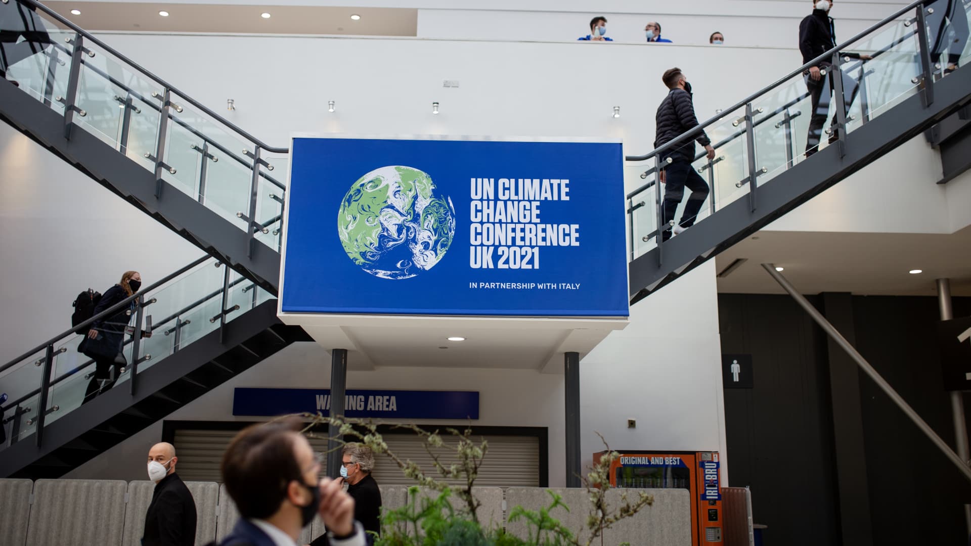 Visitors walk past a sign in the blue zone at the COP26 UN Climate Change Conference in Glasgow, U.K., on Sunday, Oct. 31, 2021.