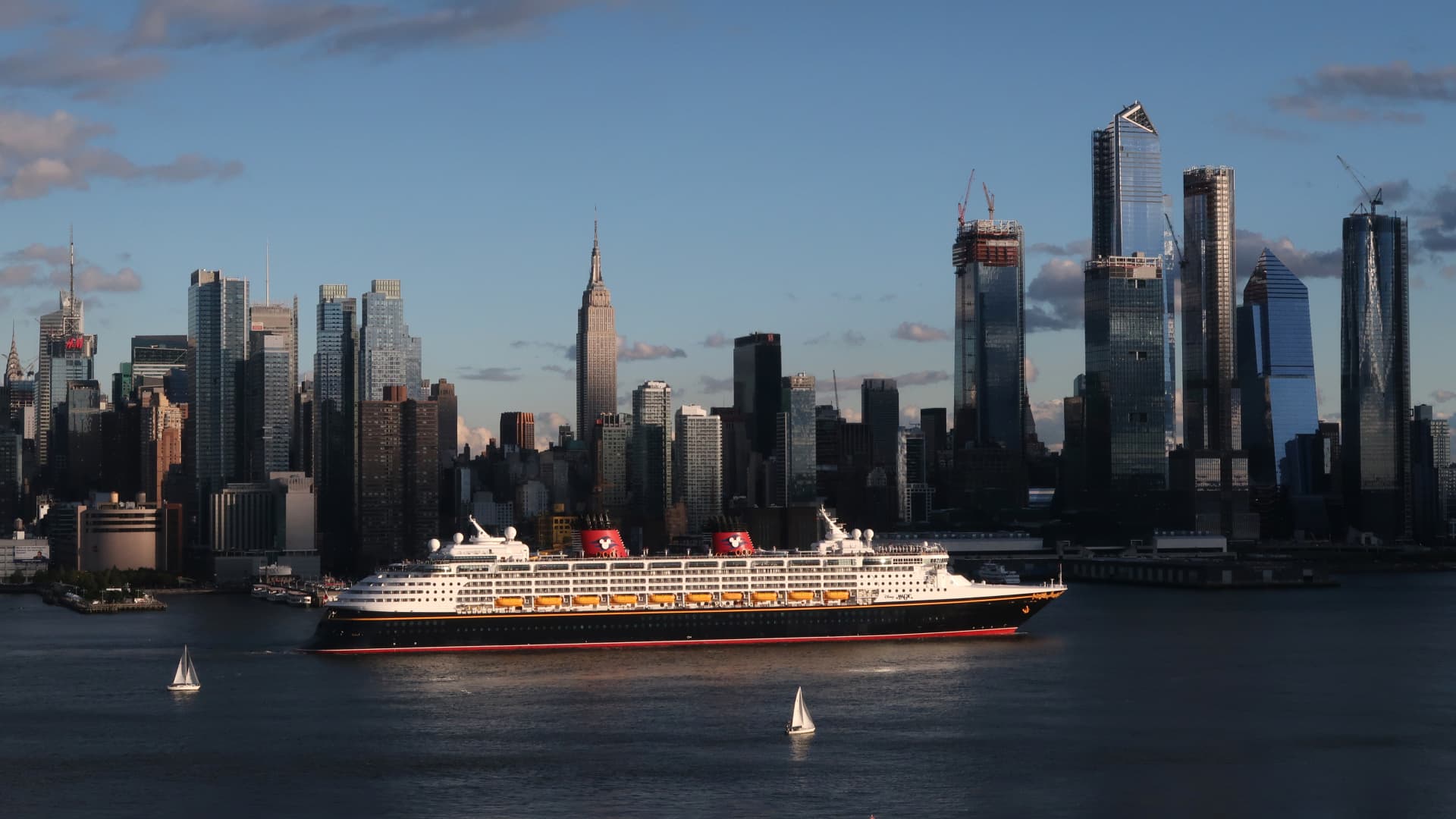 The Disney Magic cruise ship sails past Manhattan with the Empire State Building in the background.