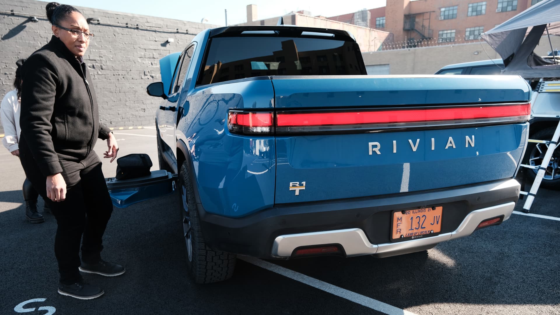 Rivian employees stand beside the new all-electric pickup truck by Rivian, the R1T, as it sits at one of its facilities on November 09, 2021 in the Brooklyn borough of New York City.