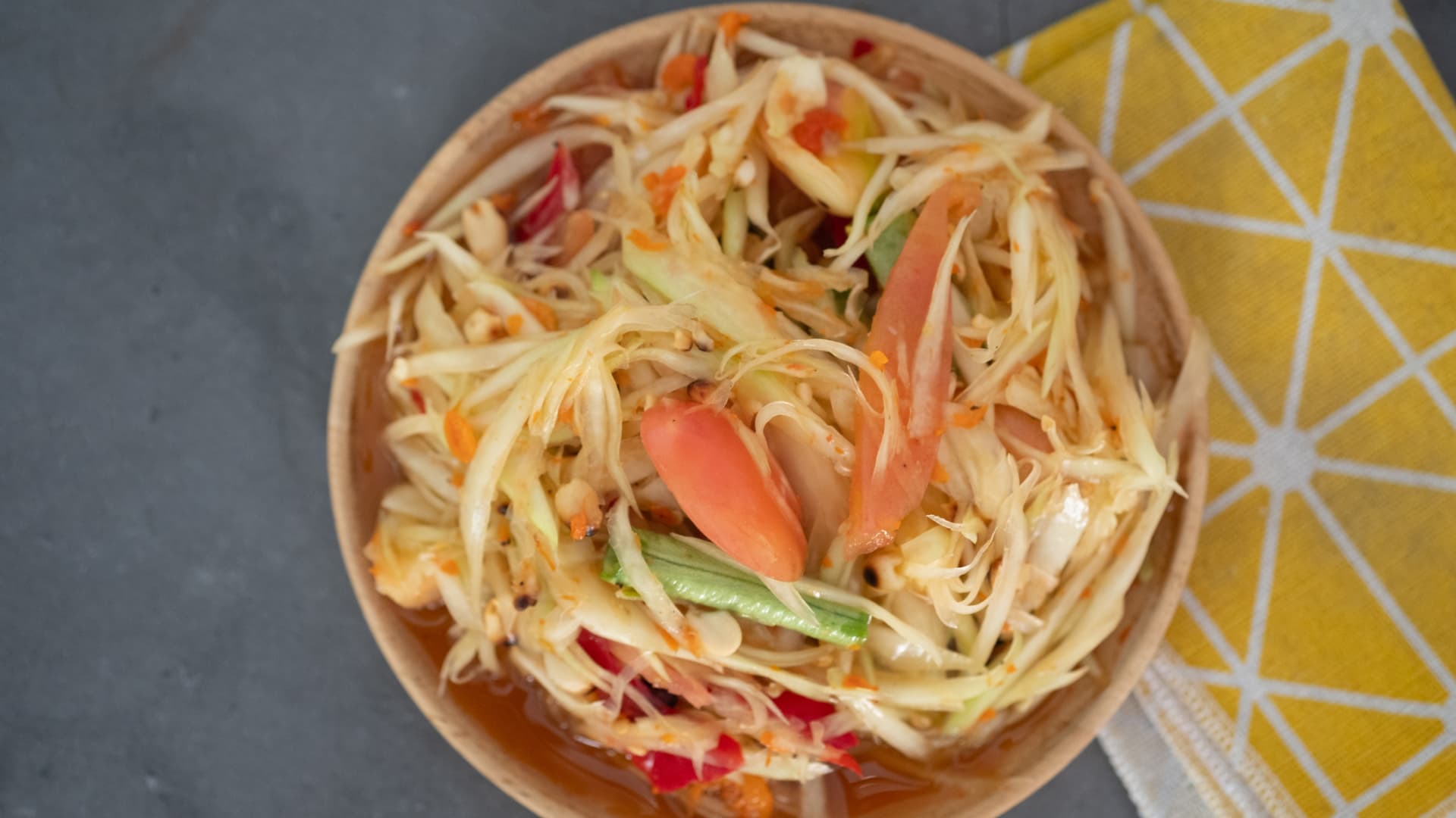 Som tam is a sweet Thai salad made with upripe papaya, long beans, lime, garlic, peanuts and sugar.