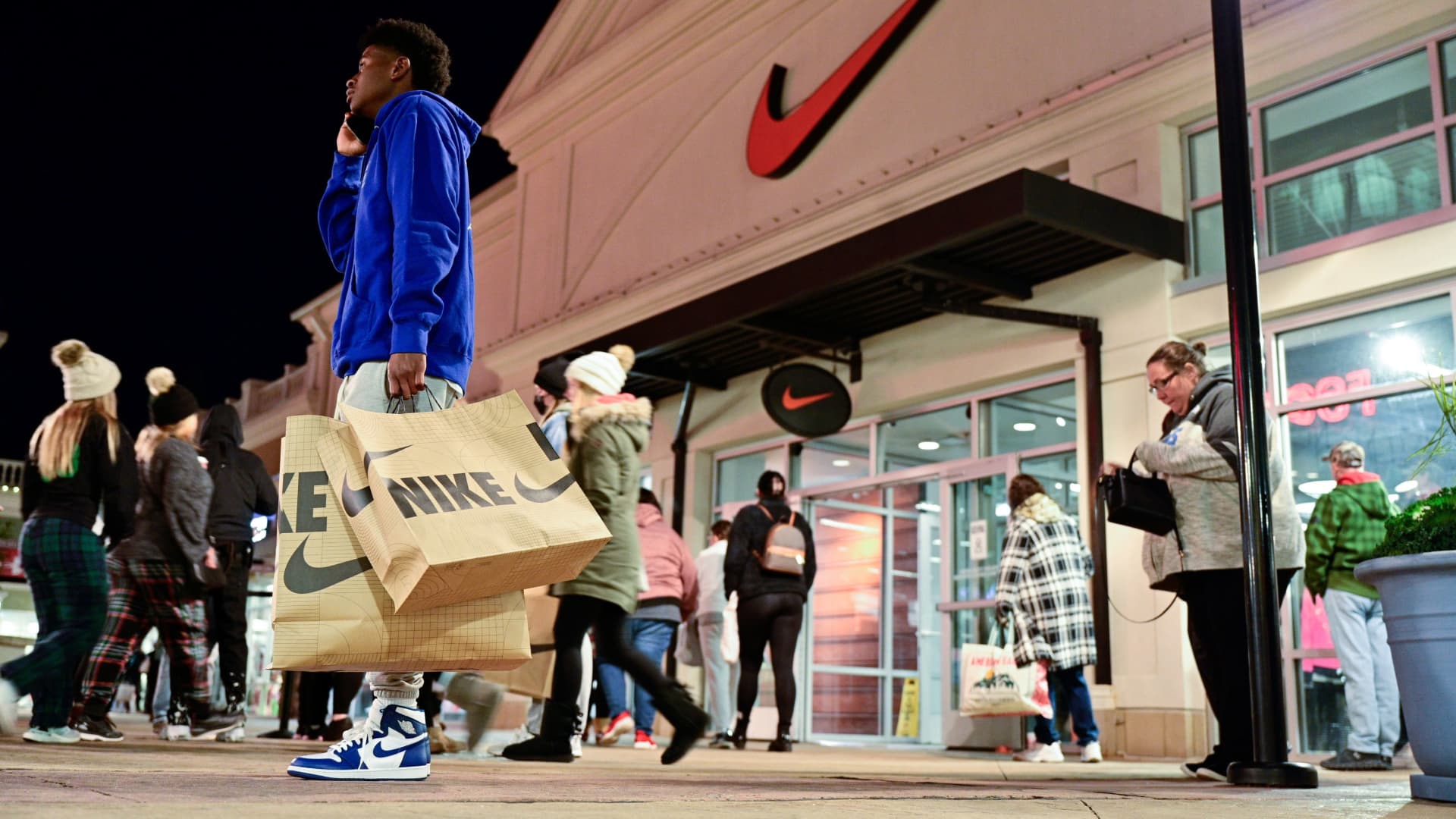 A man with Nike bags talks on the phone in front of a Nike store as Black Friday sales begin at The Outlet Shoppes of the Bluegrass in Simpsonville, Kentucky, November 26, 2021.