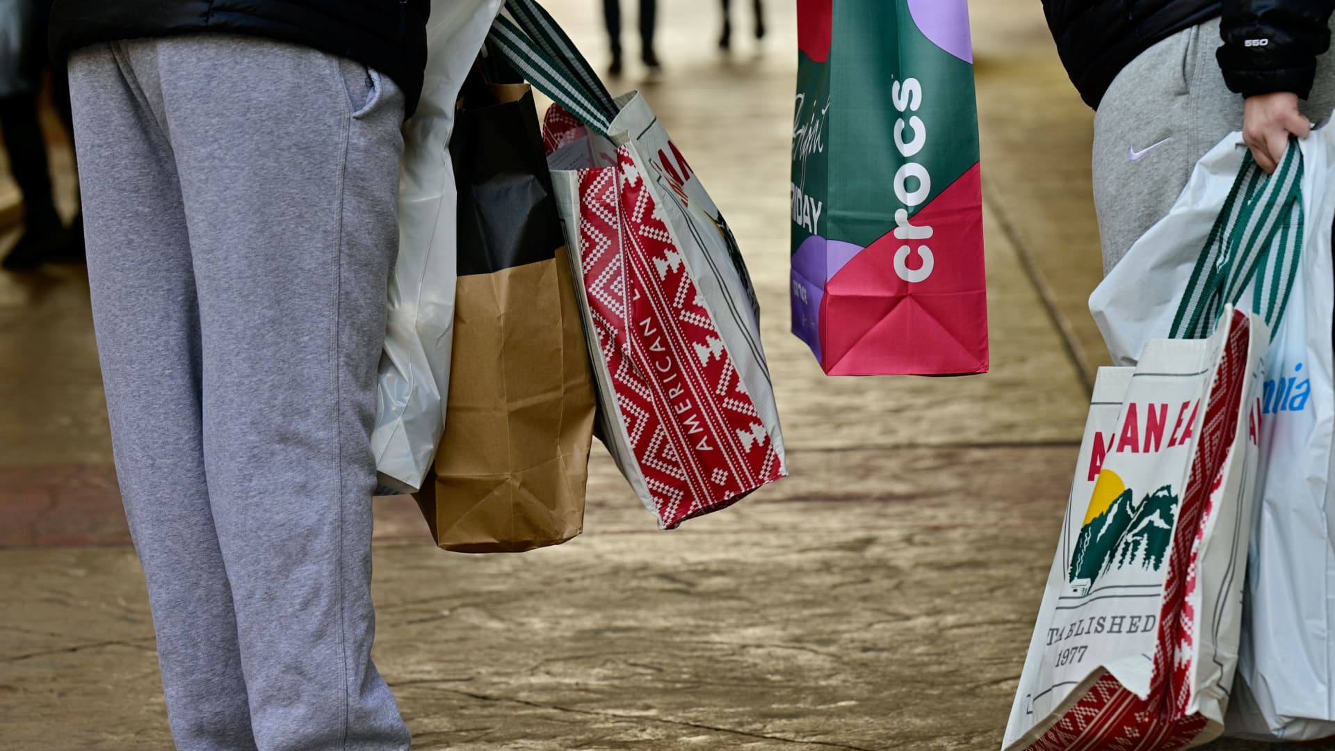 Shoppers with bags from various stores stand next to each other as Black Friday sales begin at The Outlet Shoppes of the Bluegrass in Simpsonville, Kentucky, November 26, 2021.