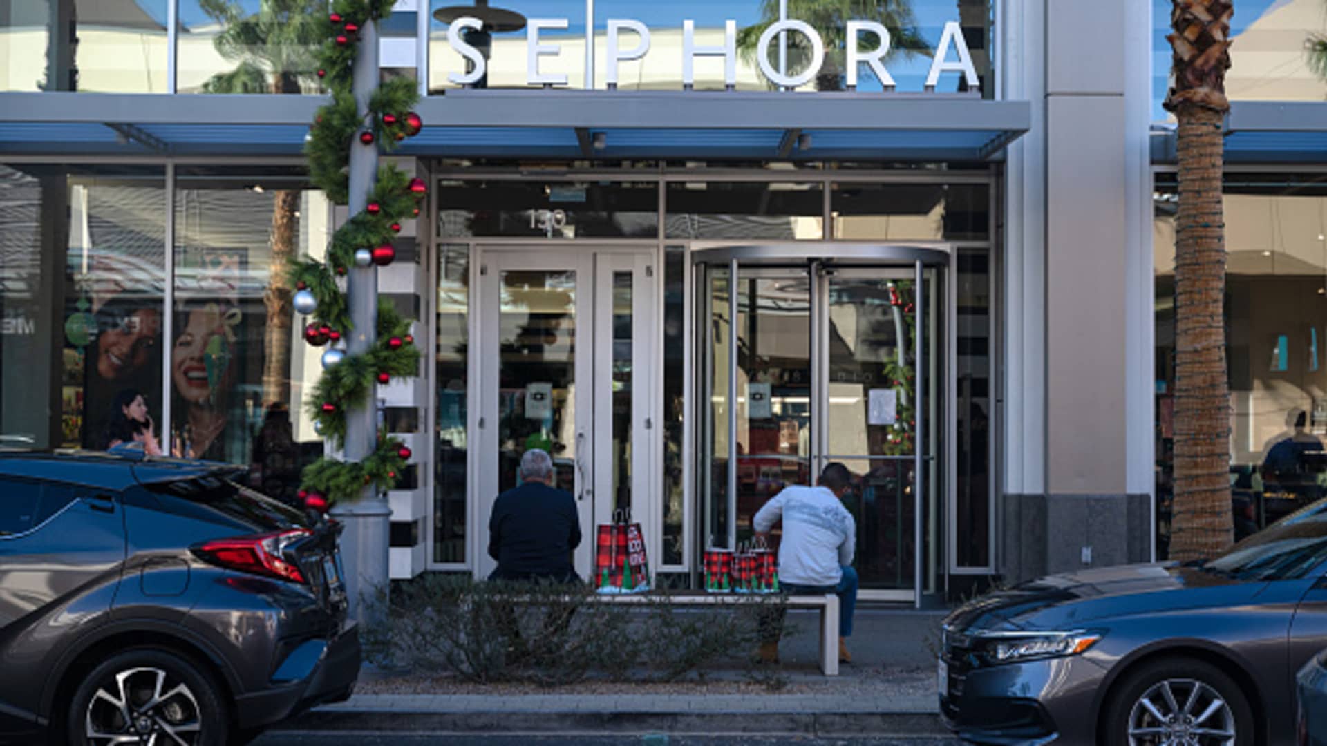 Shoppers sit outside a Sephora store with holiday shopping bags in Las Vegas, Nevada, on Sunday, Nov. 7, 2021.
