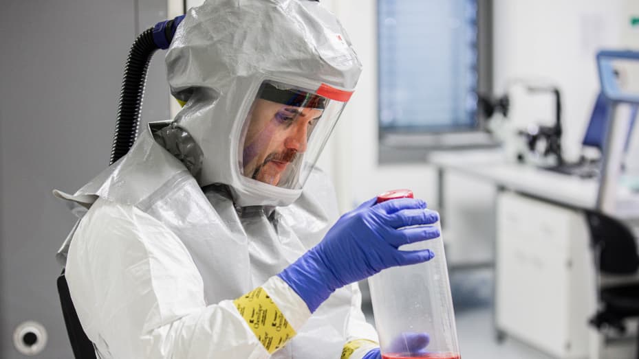 Un técnico de laboratorio que lleva un traje de protección de cuerpo completo manipula una botella que contiene medios de crecimiento para la producción de virus durante la investigación de la vacuna contra el coronavirus en los laboratorios de Valneva SA en Viena, Austria.