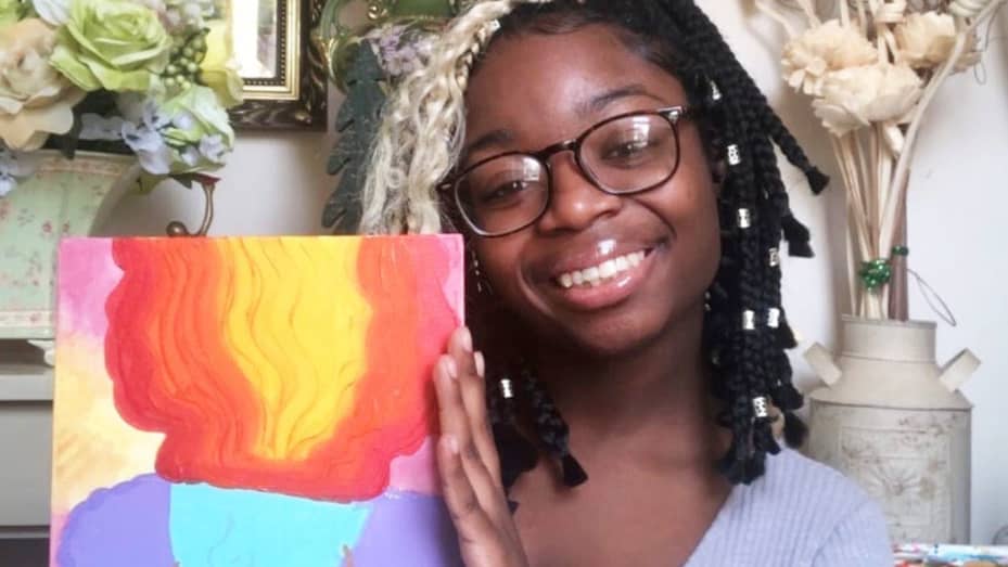 Kerisa Mason holding her painting of "Girl on Fire" from her custom-made art business