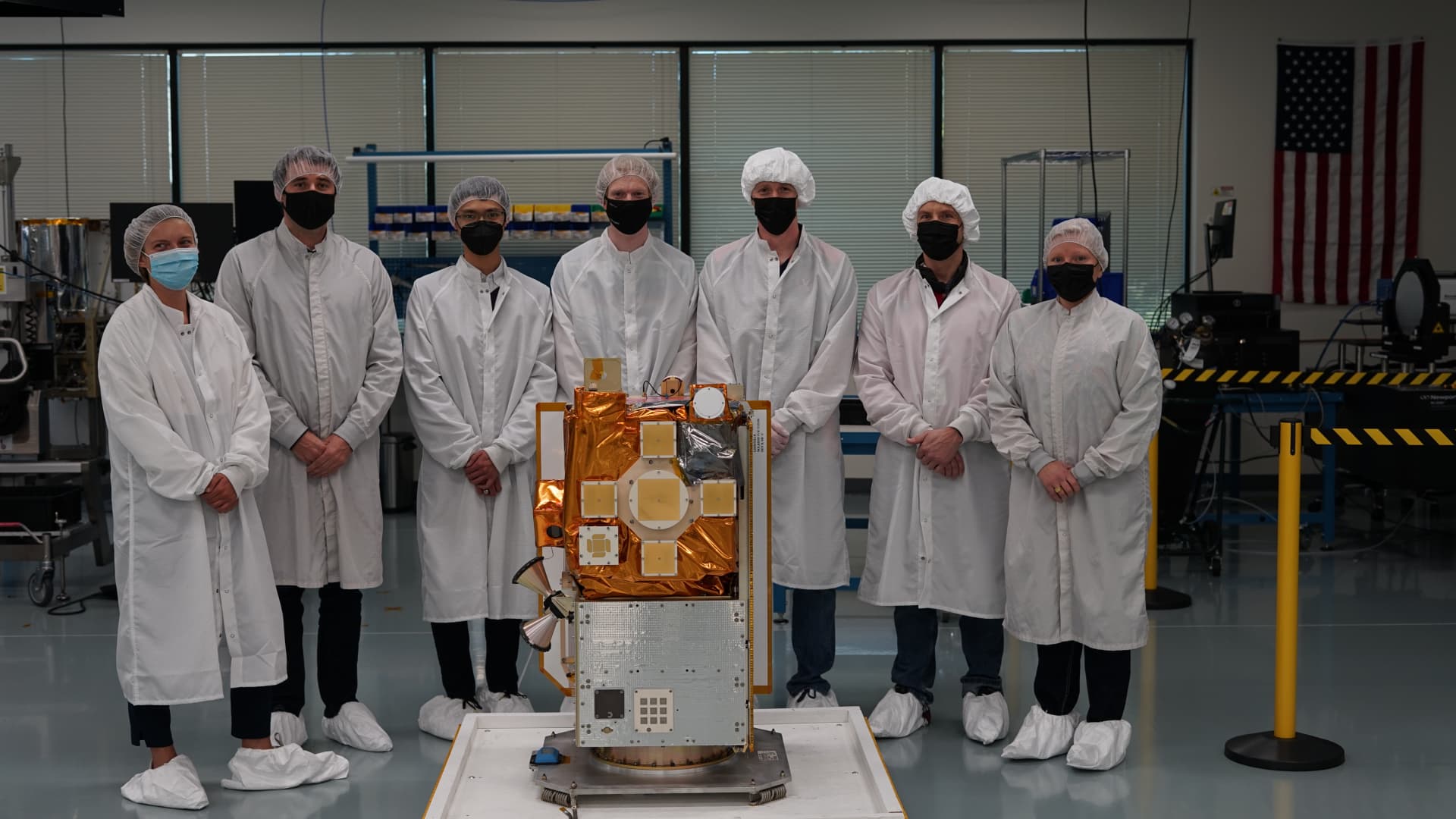 A team of company engineers stand around the YAM-3 spacecraft.