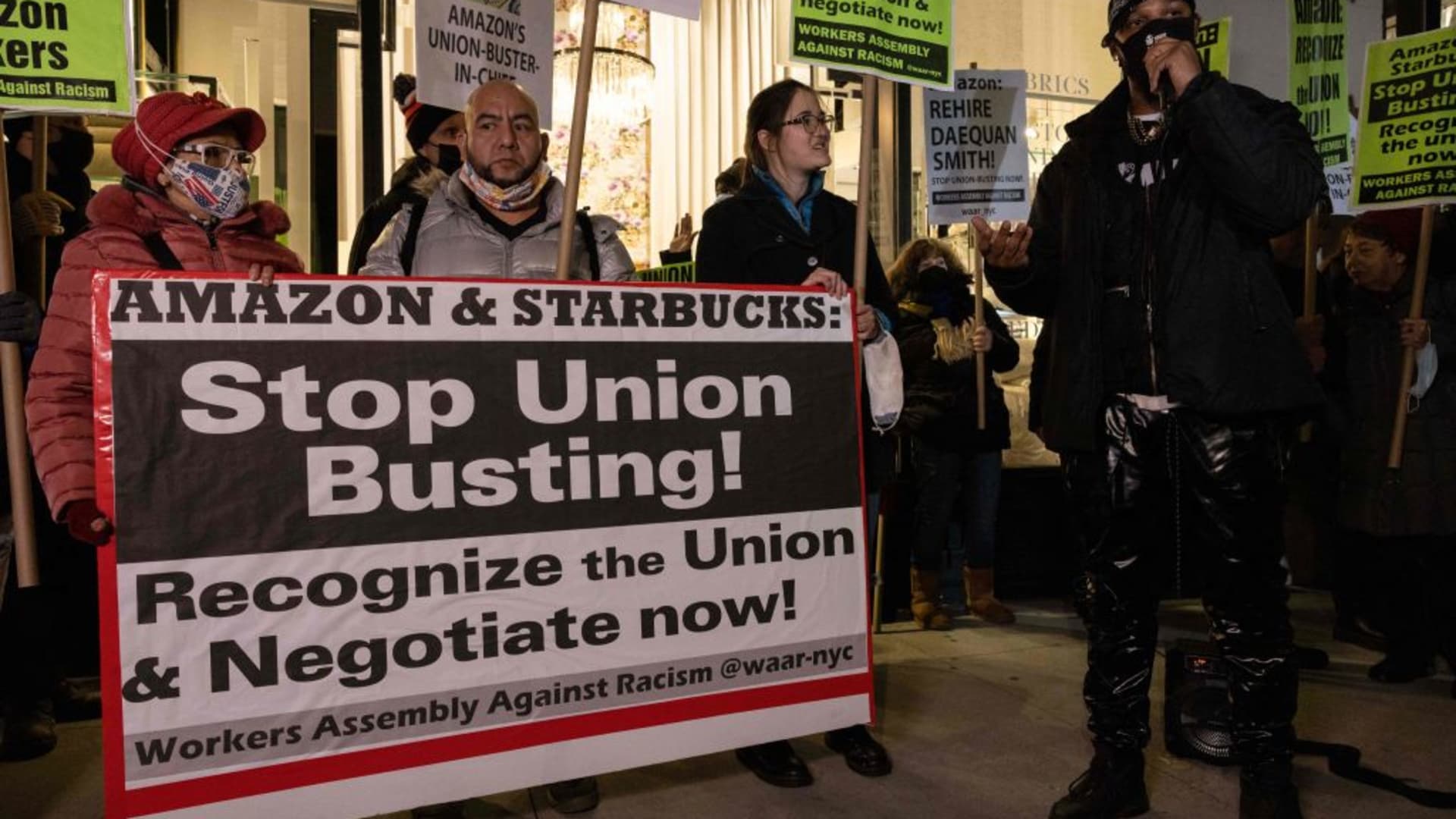 People hold placards during a protest in support of Amazon and Starbucks workers in New York City on November 26, 2021.