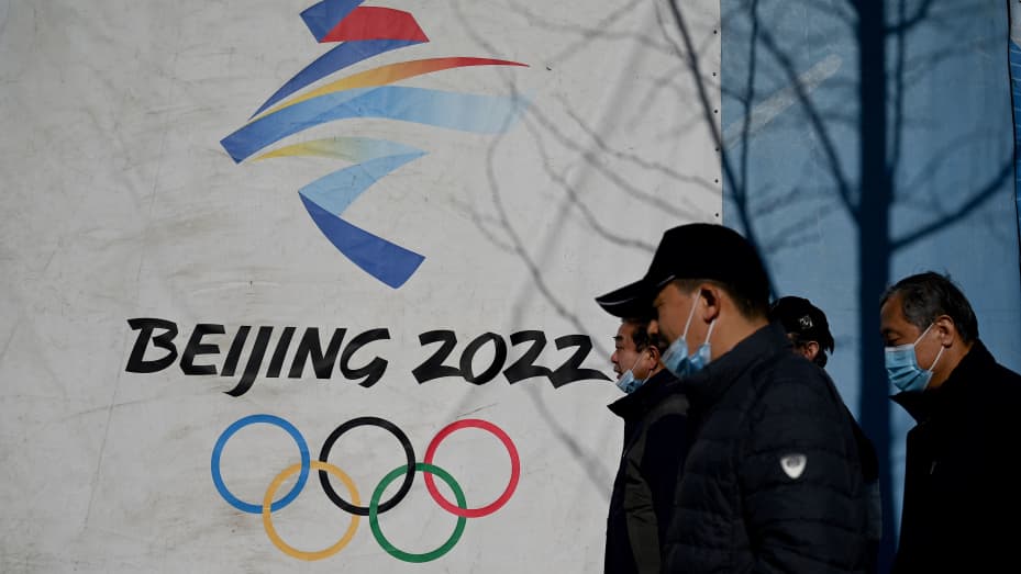 People walk past the Beijing 2022 Winter Olympics logo at the Shougang Park in Beijing on December 1, 2021.