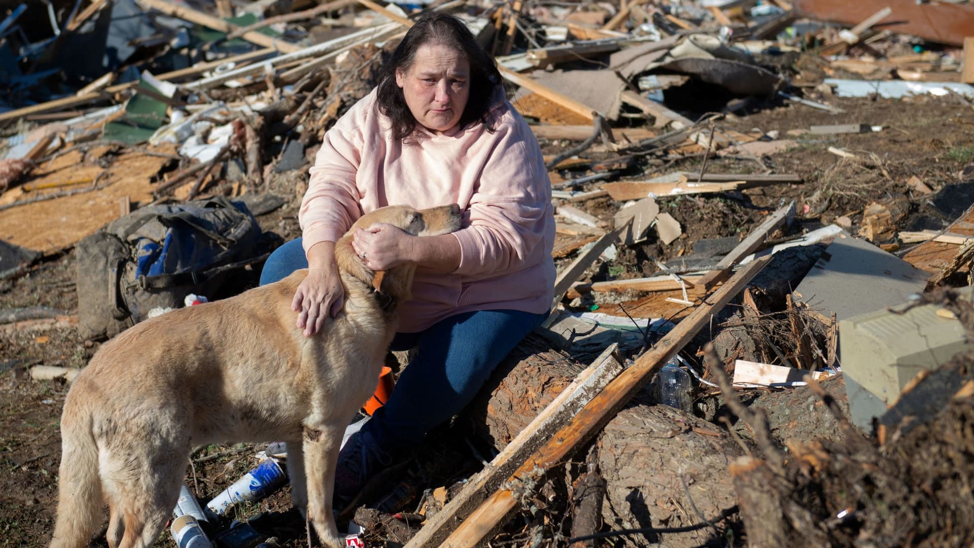Charlene Stanley of Central City, Kentucky holds dog Gus as they search the debris that once was her sister-in-law's home after the tornado in Bremen, Kentucky, U.S. December 12, 2021.
