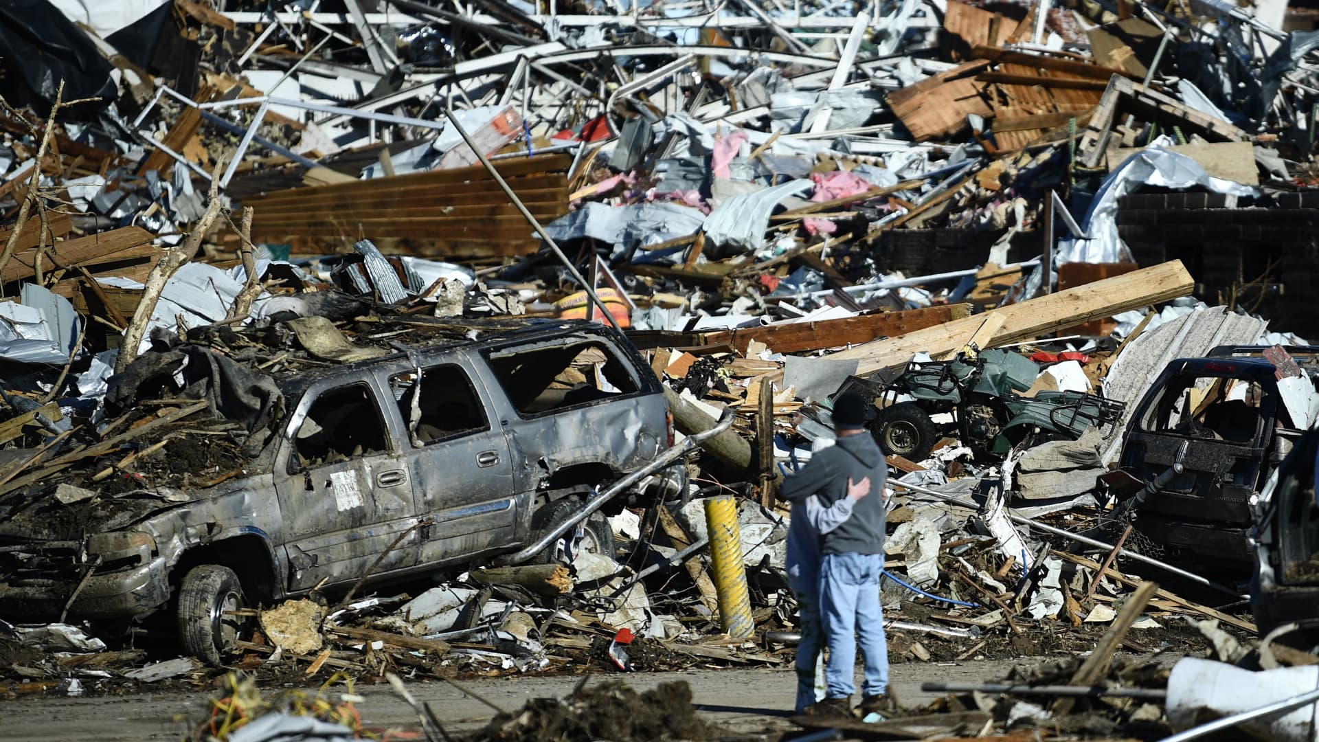People embrace as tornado damage is seen after extreme weather hit the region December 12, 2021, in Mayfield, Kentucky.