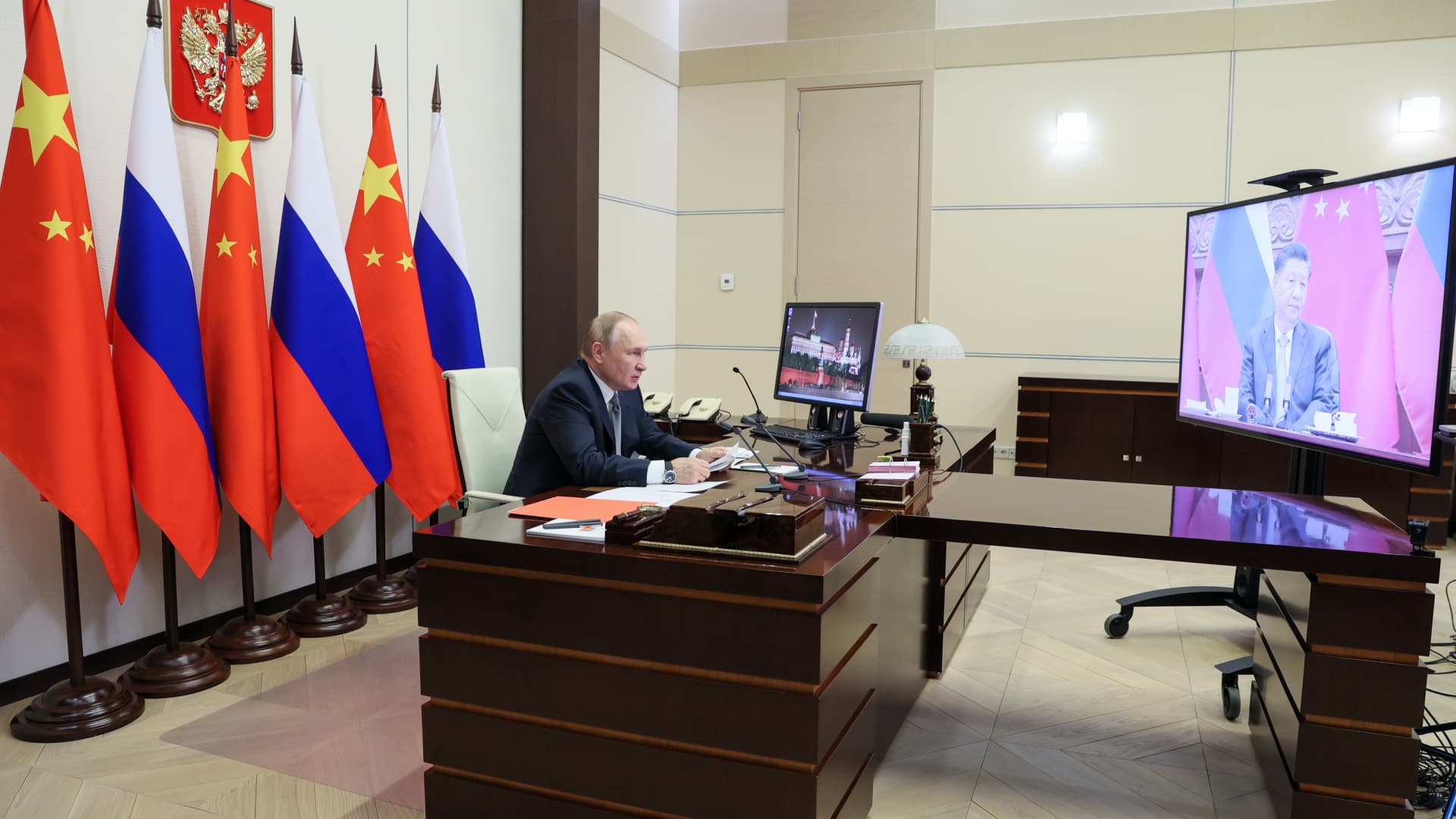 Russia's President Vladimir Putin sits in his office in the Novo-Ogaryovo residence during a bilateral meeting with China's President Xi Jinping (on the video screen) via a video call.