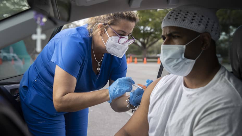 Alejandro Brown receives a Pfizer-BioNTech COVID-19 vaccine from a healthcare worker at a drive-thru site at Tropical Park on December 16, 2021 in Miami, Florida.