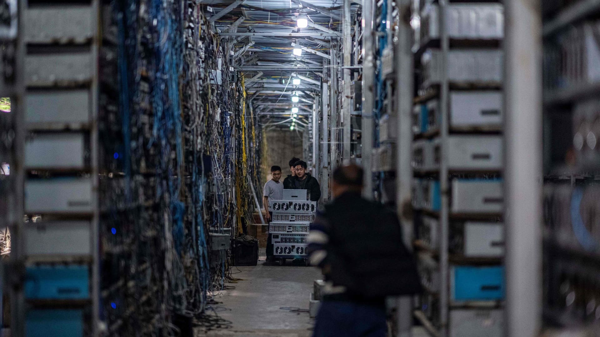 Workers transferring cryptocurrency mining rigs at a farm in Sichuan province