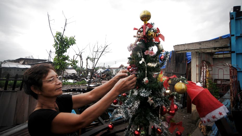 Linda Abella, 63, fixes the decorations on her Christmas tree outside her house in typhoon-hit Palo, Philippines on Dec. 23, 2013.