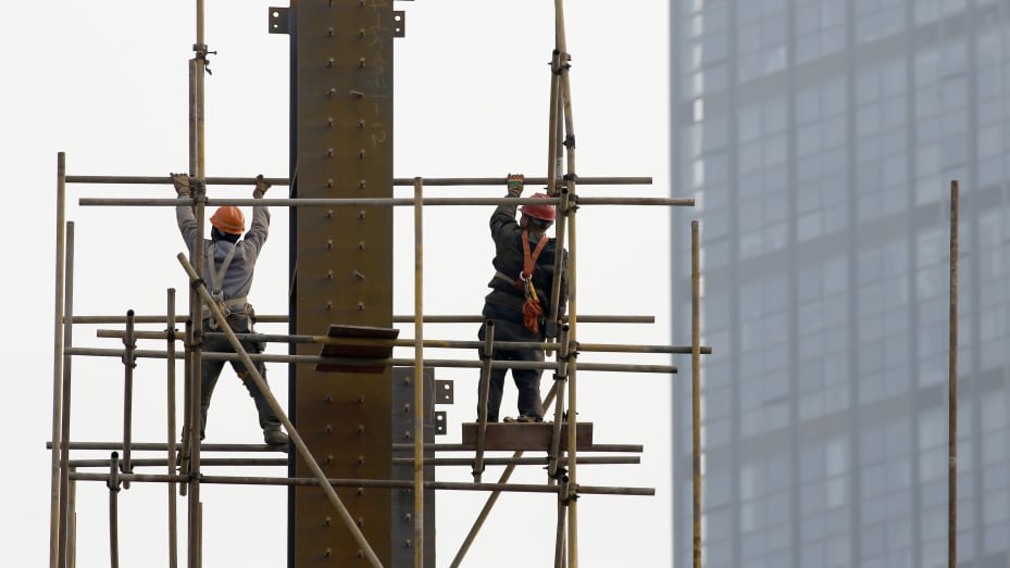 Trabajadores migrantes construyen un andamio en el sitio de construcción de la Fase II de la ciudad comercial de Huayang en la ciudad de Huai 'an, provincia de Jiangsu, en el este de China, el 7 de febrero de 2021.