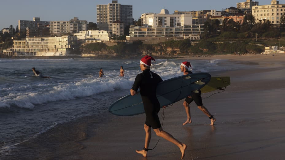 Surfistas con gorros de Papá Noel se dirigen al agua en Bondi Beach al amanecer el 25 de diciembre de 2021 en Sydney, Australia.