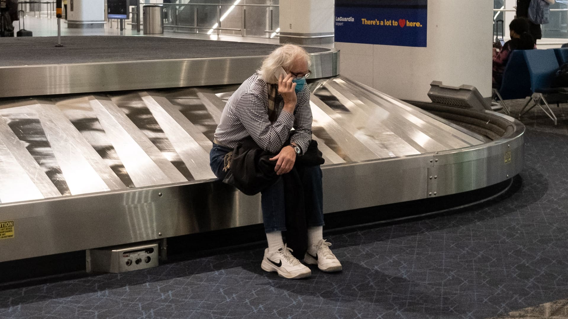 A traveler sits in baggage claim at LaGuardia Airport in New York, on December 24, 2021.