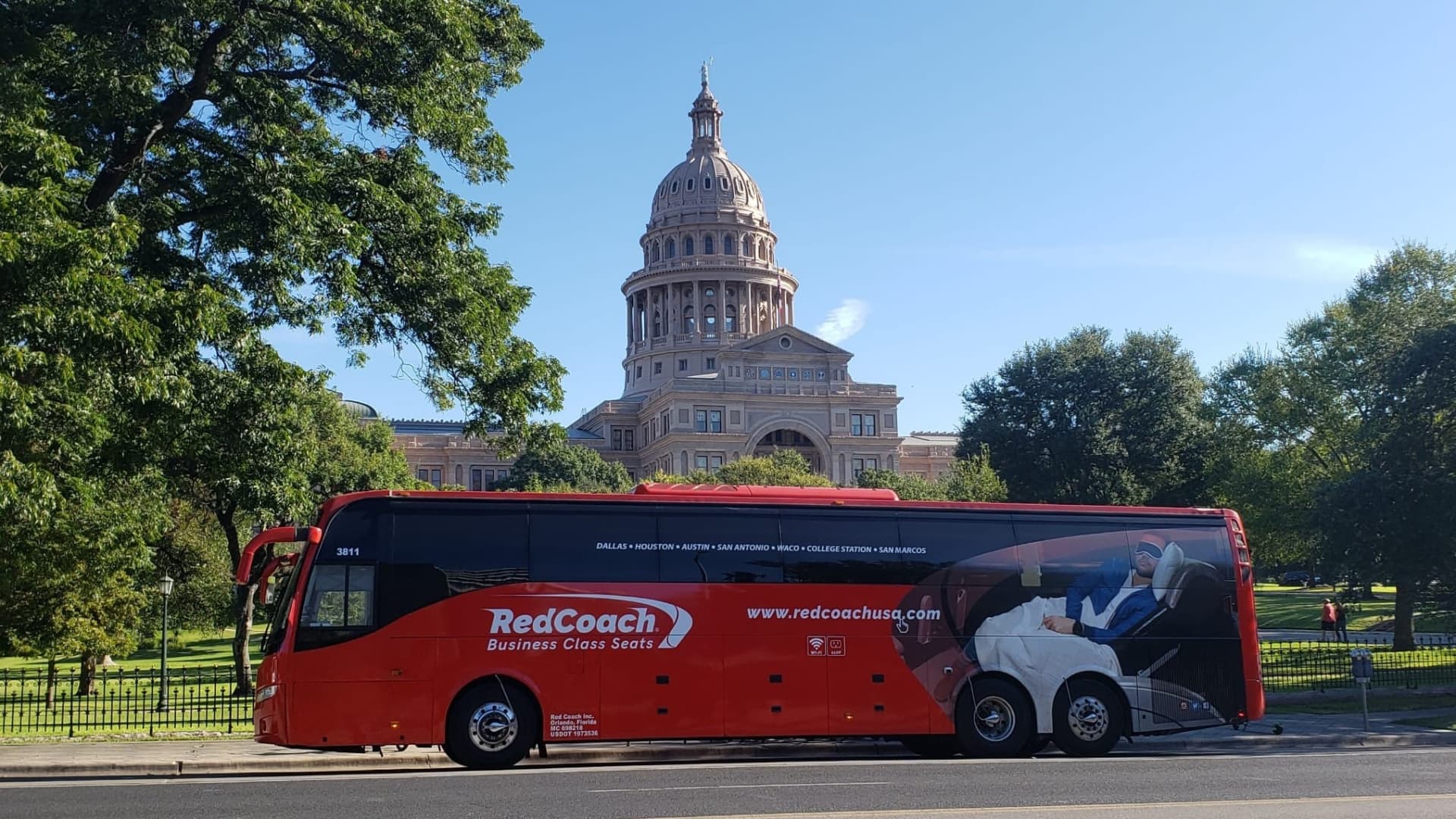 A RedCoach business-class motorcoach passes the Texas Capitol in Austin.