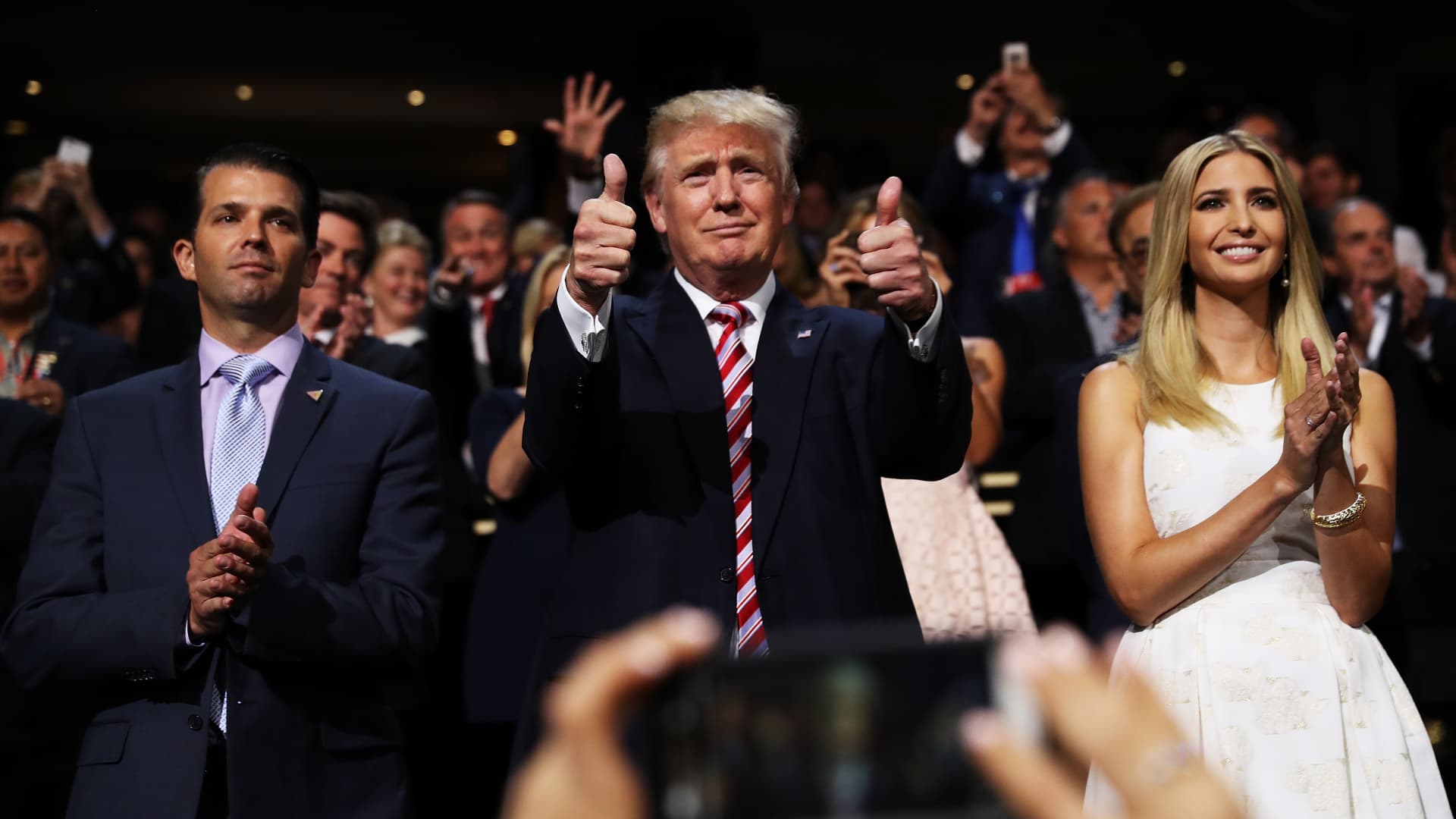 Republican presidential candidate Donald Trump (C) gives two thumbs up as Donald Trump Jr. (L) and Ivanka Trump (R) stand and cheer for Eric Trump as he delivers his speech during the third day of the Republican National Convention on July 20, 2016 at the Quicken Loans Arena in Cleveland, Ohio.