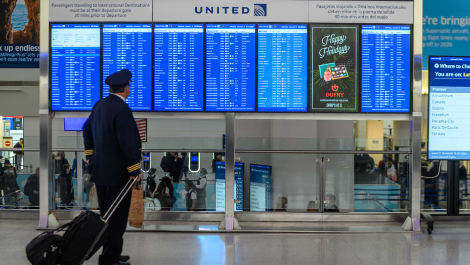 A pilot views a departure board at Newark Liberty International Airport (EWR) in Newark, New Jersey, on Monday, Jan. 3, 2022.
