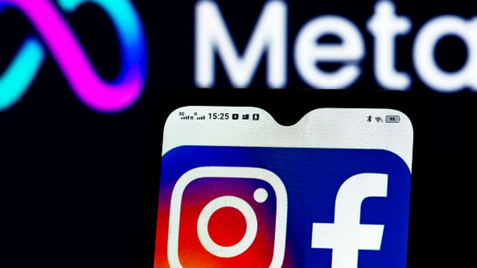 The Facebook and Instagram logos displayed on a smartphone with the Meta Platforms logo pictured in the background.