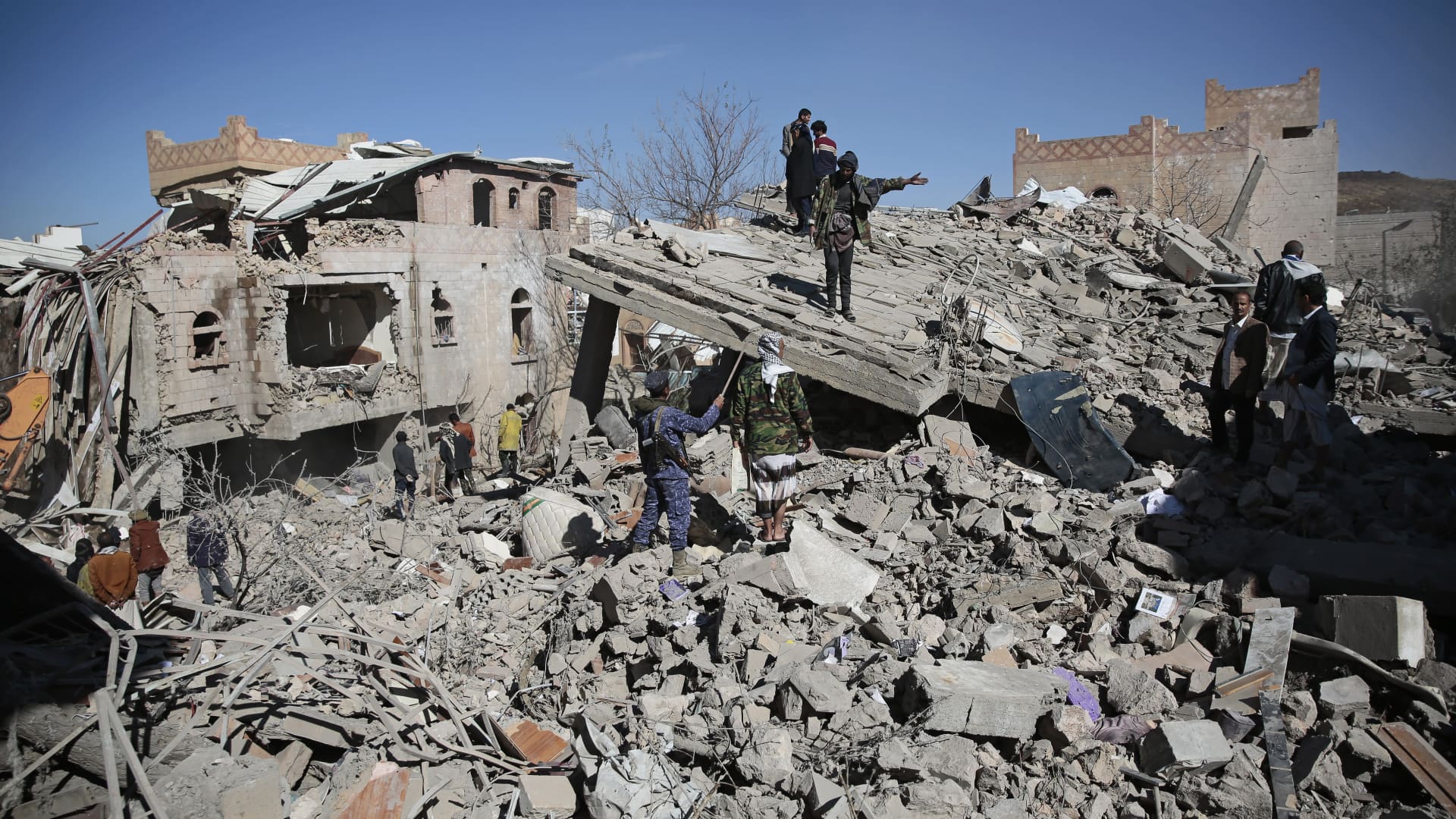 Yemenis inspect the wreckage of buildings after they were hit by Saudi-led coalition airstrikes, in Sanaa, Yemen, Tuesday, Jan. 18, 2022. The coalition fighting in Yemen announced it had started a bombing campaign targeting Houthi sites a day after a fatal attack on an oil facility in the capital of the United Arab Emirates claimed by Yemen's Houthi rebels.