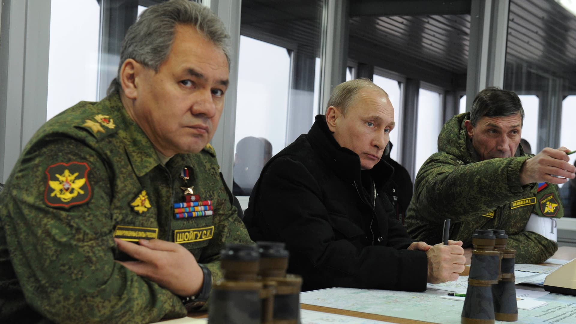 Russia's President Vladimir Putin (C) listens to the head of the Russian army's main department of combat preparation Ivan Buvaltsev (R) while watching military exercises at the Kirillovsky firing ground in the Leningrad region, on March 3, 2014, with Defence Minister Sergei Shoigu (L)attending.