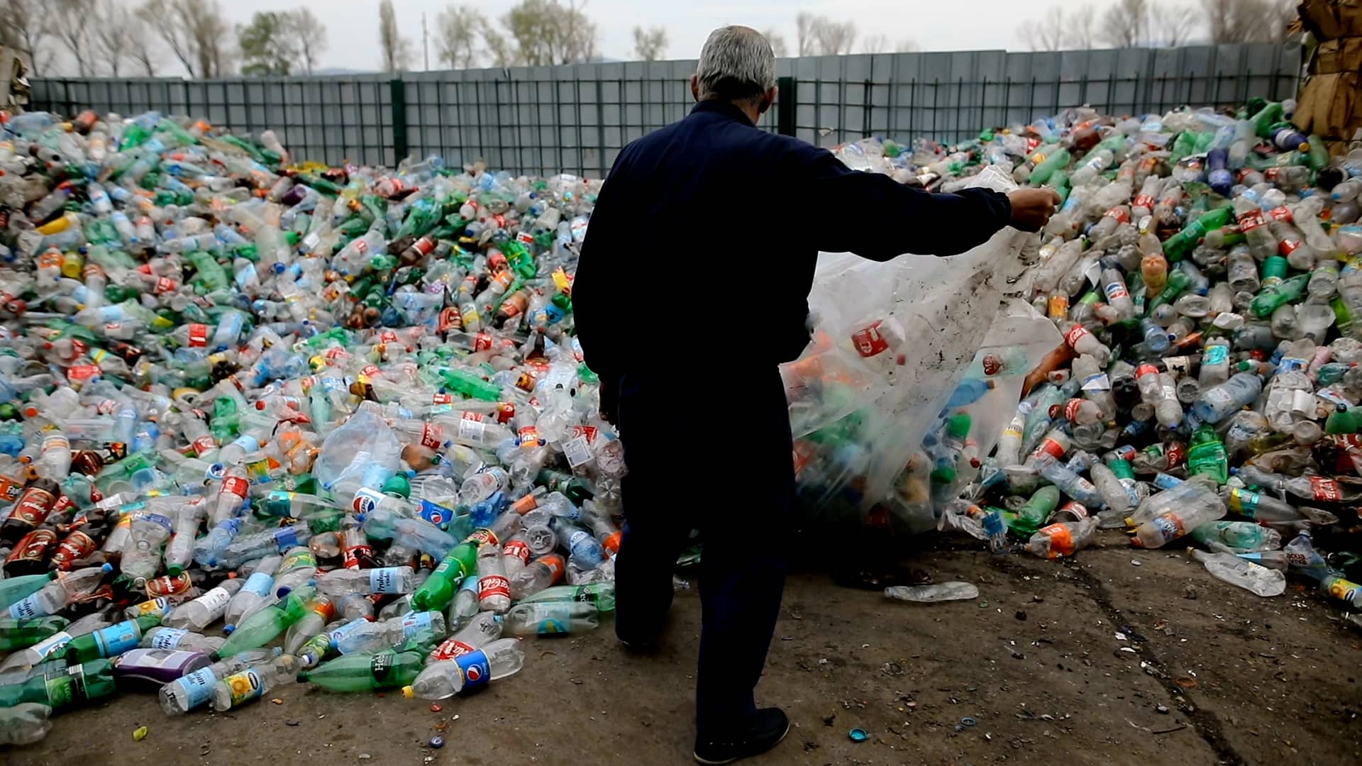 A sanitary worker deals with an influx of plastic bottles at a recycling center in Serbia