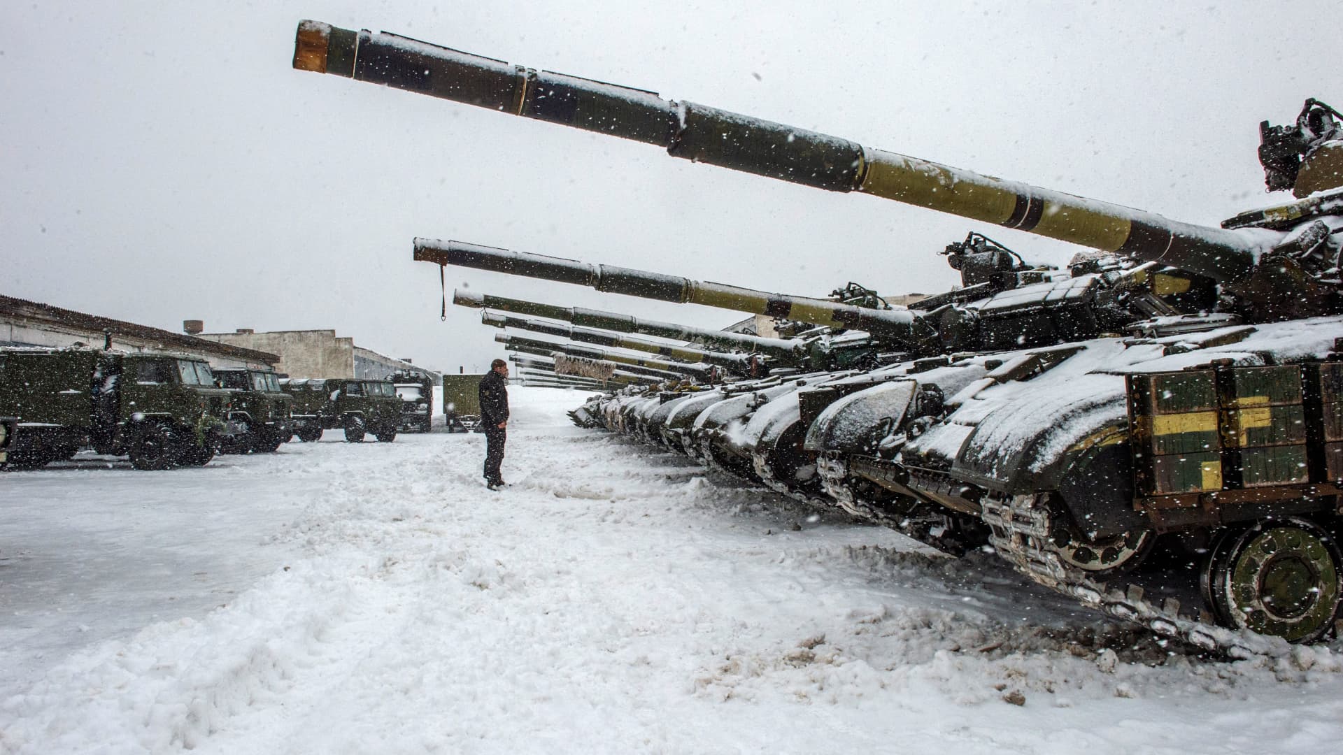 An Ukrainian Military Forces serviceman stands in front of tanks of the 92nd separate mechanized brigade of Ukrainian Armed Forces, parked in their base near Klugino-Bashkirivka village, in the Kharkiv region on January 31, 2022.