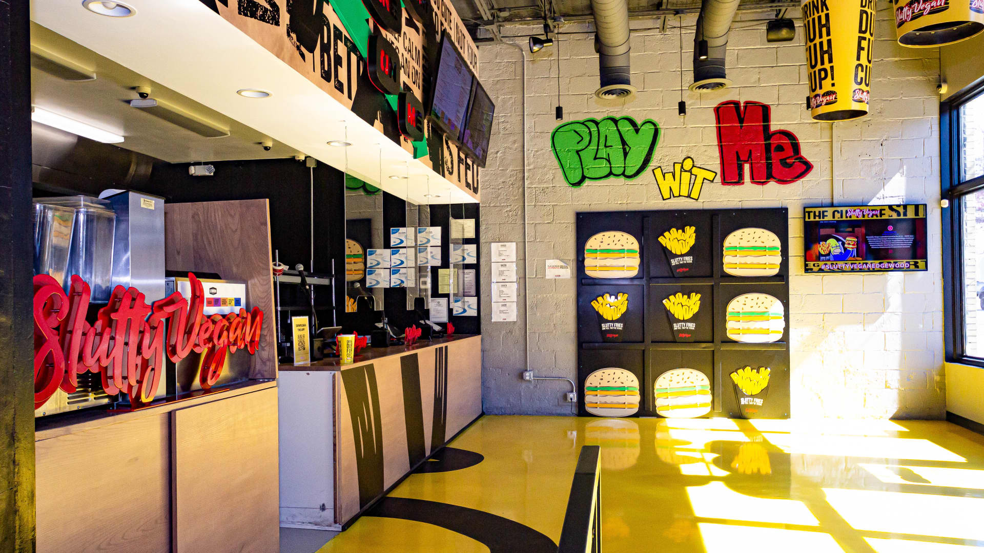 The interior of a Slutty Vegan location in Atlanta, featuring bright colors and graffiti-inspired artwork.