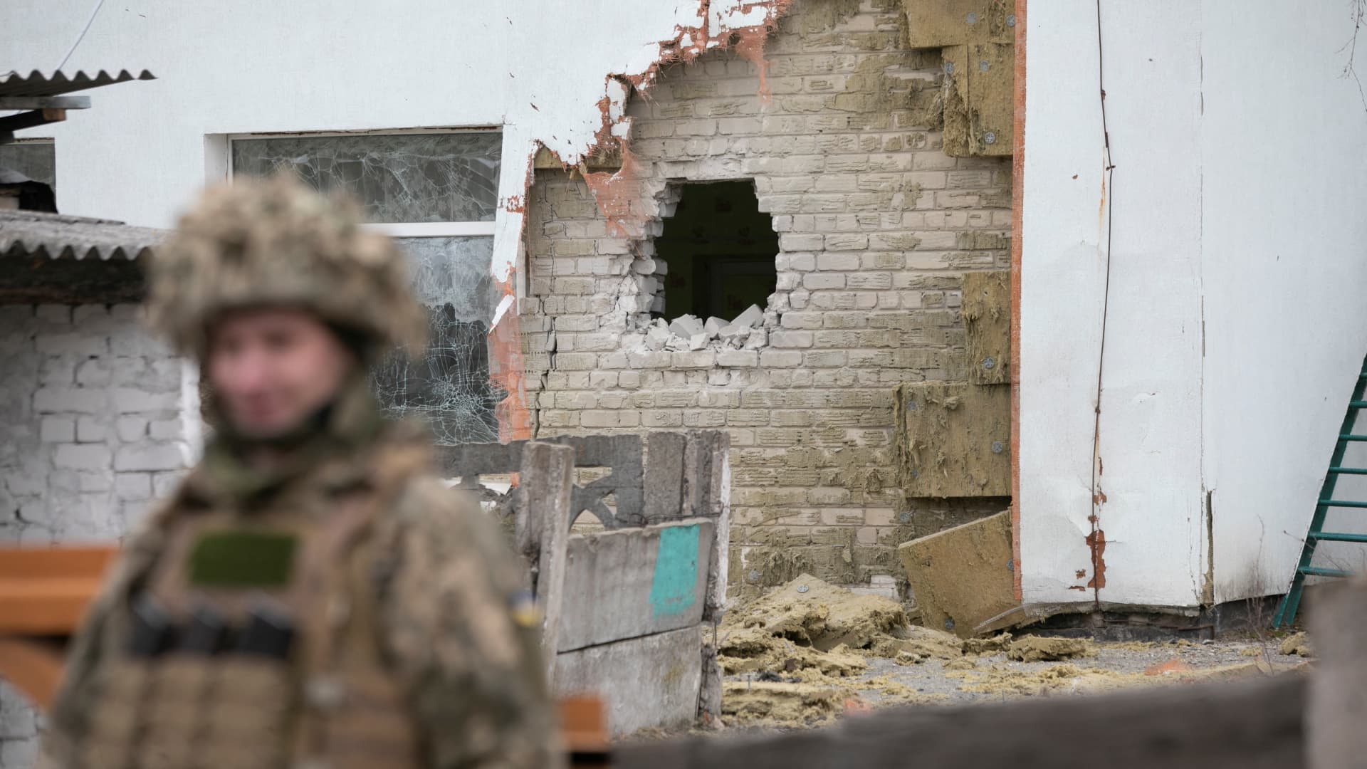 A Ukrainian soldier stands next to a damaged wall after the reported shelling of a kindergarten in the settlement of Stanytsia Luhanska, Ukraine, on February 17, 2022.