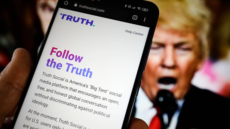 The TRUTH Social website is seen on a mobile device with an image of former US president Donald Trump in the background in this photo illustration in Warsaw, Poland on 23 February, 2022.