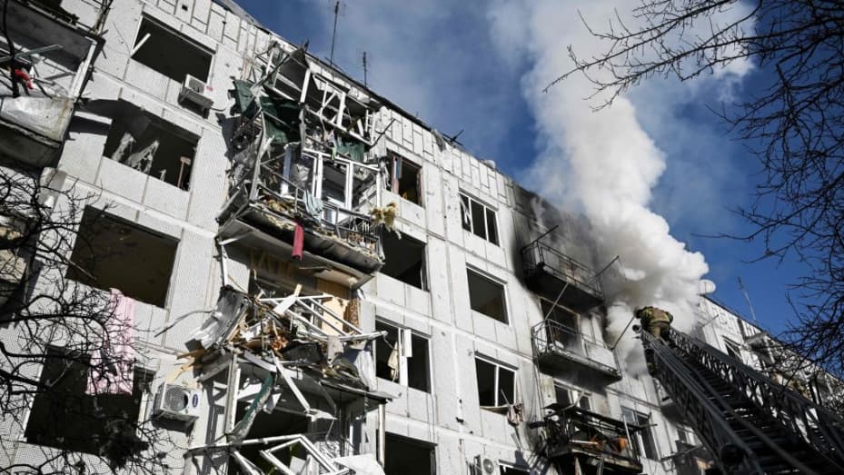 Bombeiros trabalham em um incêndio em um prédio após bombardeios na cidade de Chuguiv, no leste da Ucrânia, em 24 de fevereiro de 2022, enquanto as forças armadas russas tentam invadir a Ucrânia de várias direções, usando sistemas de foguetes e helicópteros para atacar po ucraniano.