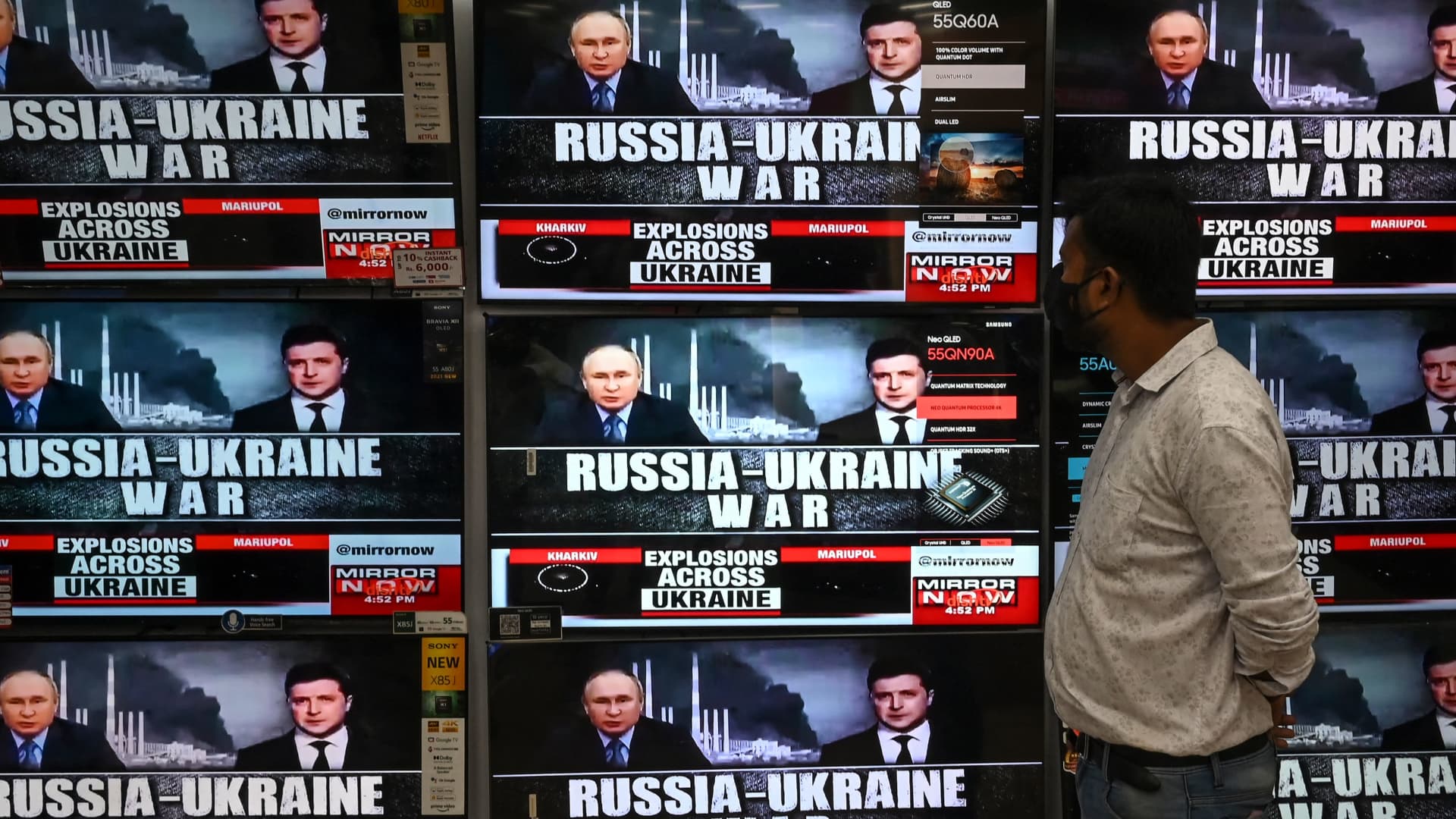 A man watches a coverage of the conflict between Russia and Ukraine displayed on televisions in Kolkata on February 24, 2022.