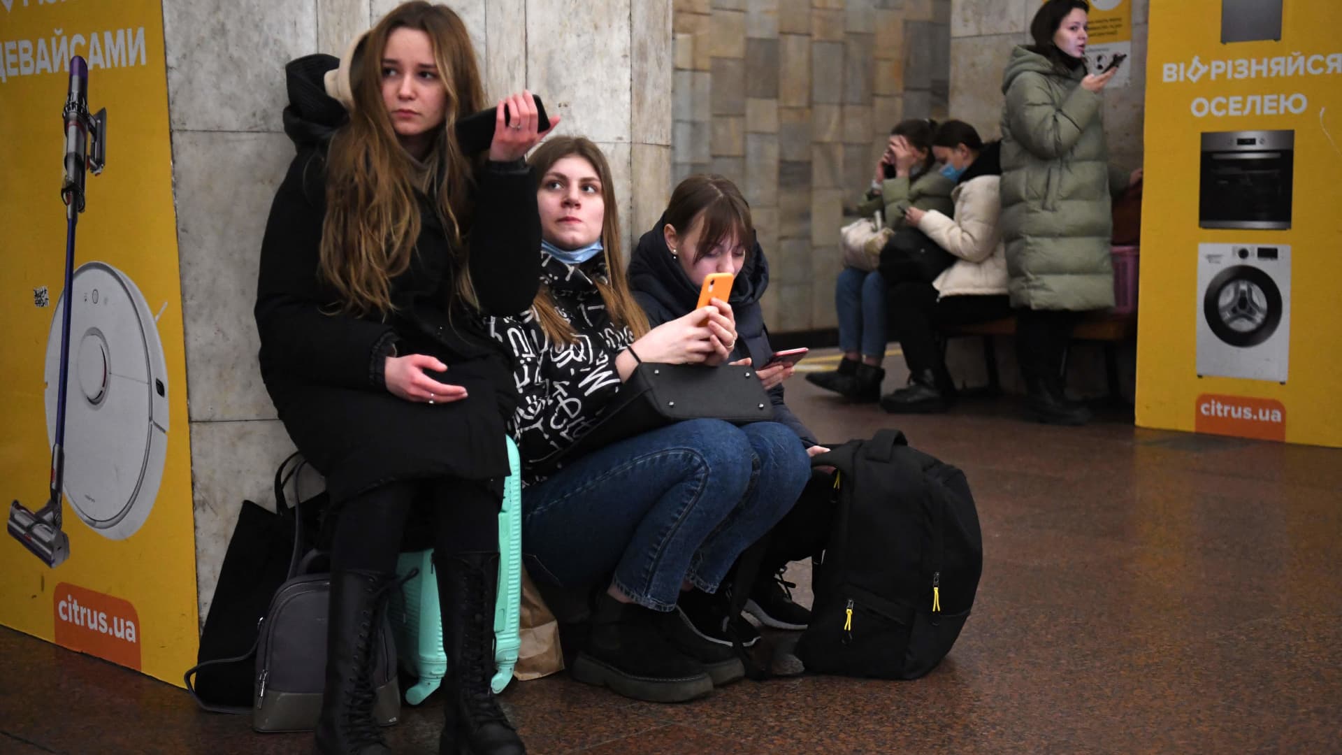 Girls hold their mobile phone as they take refuge in a metro station in Kyiv in the morning of February 24, 2022.