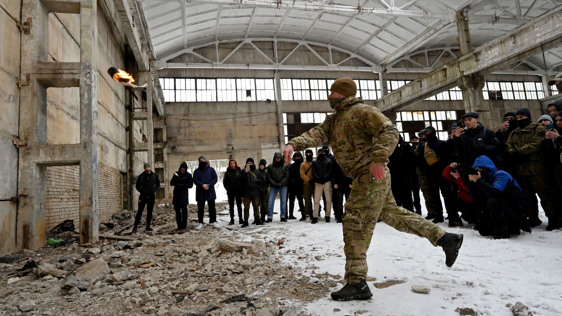 A military instructor teaches civilians to use Molotov cocktails during a training session at an abandoned factory in the Ukrainian capital of Kyiv on February 6, 2022.