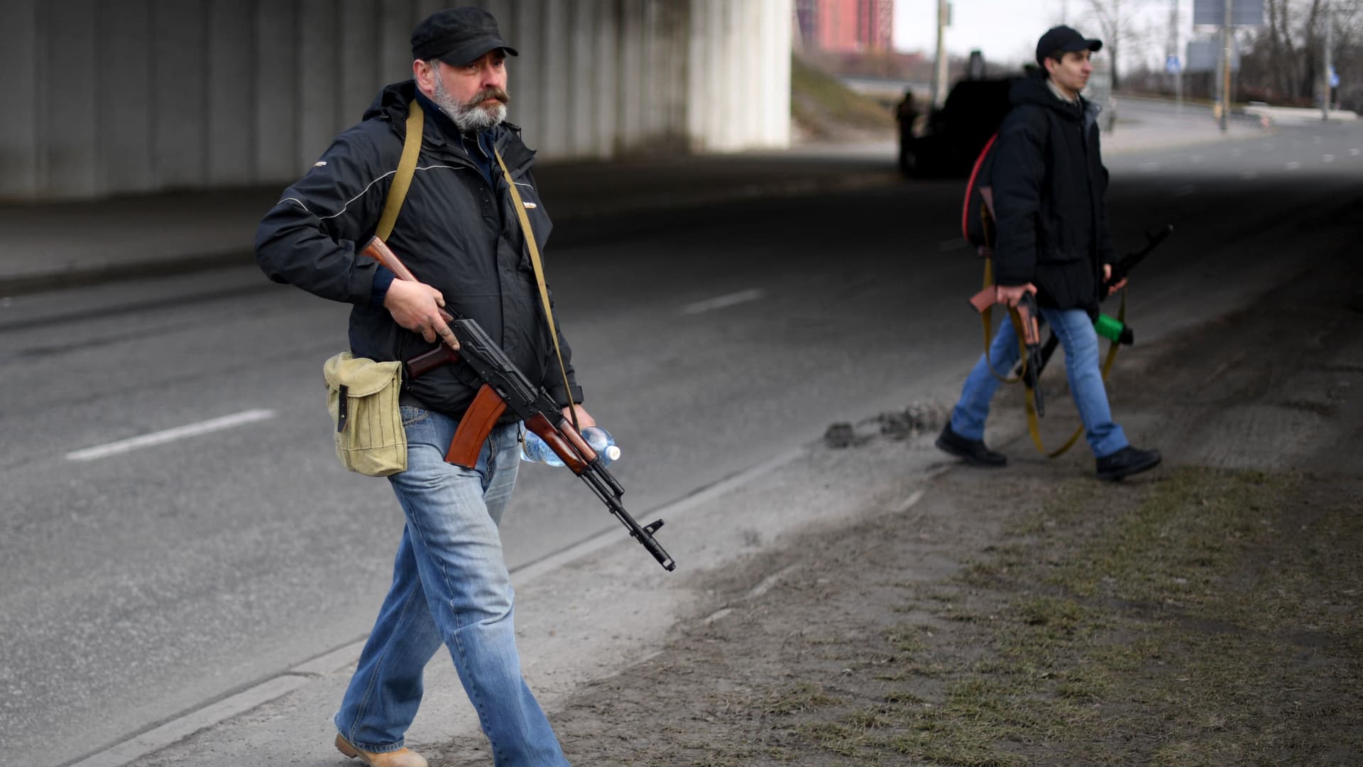 Volunteers, one holding an AK-47 rifle, protect a main road leading into Kyiv on February 25, 2022.