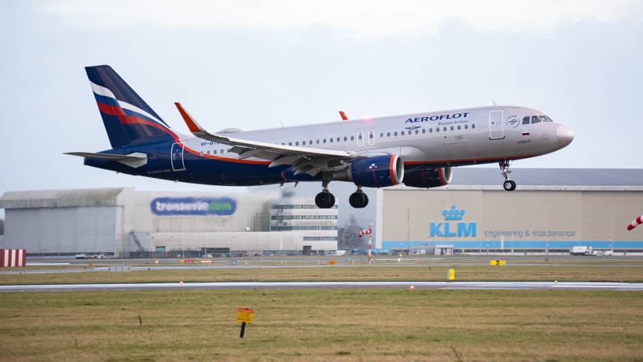 An Aeroflot - Russian Airlines Airbus A320 aircraft as seen on final approach flying and landing on the runway at Amsterdam Schiphol Airport with the terminal and the control tower visible, after arriving from Moscow.
