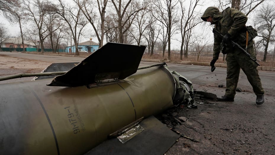 A militant of the self-proclaimed Donetsk People's Republic inspects the remains of a missile that landed on a street in the separatist-controlled city of Donetsk, Ukraine February 26, 2022.