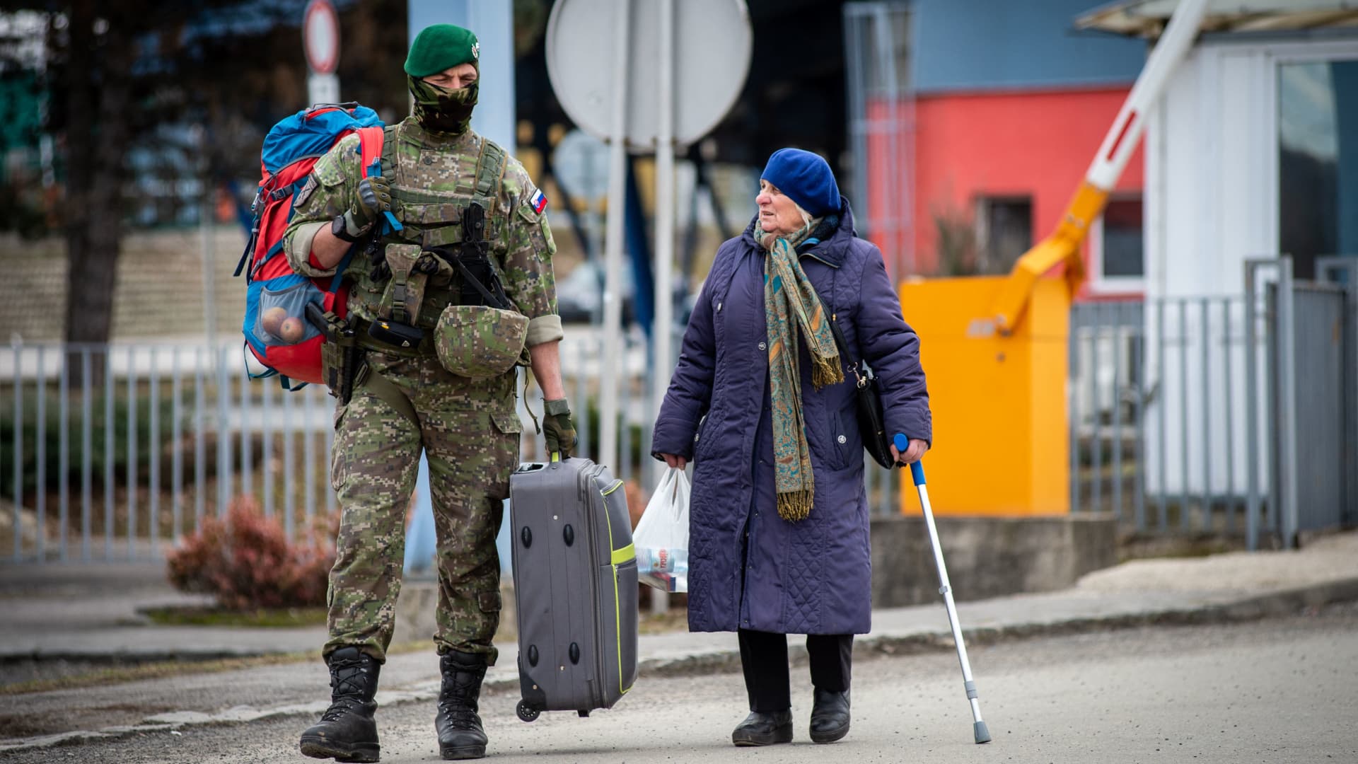 A Slovak soldier helps a Ukrainian woman to carry her luggage after after she crossed the border in Vysne Nemecke, eastern Slovakia, on February 26, 2022.
