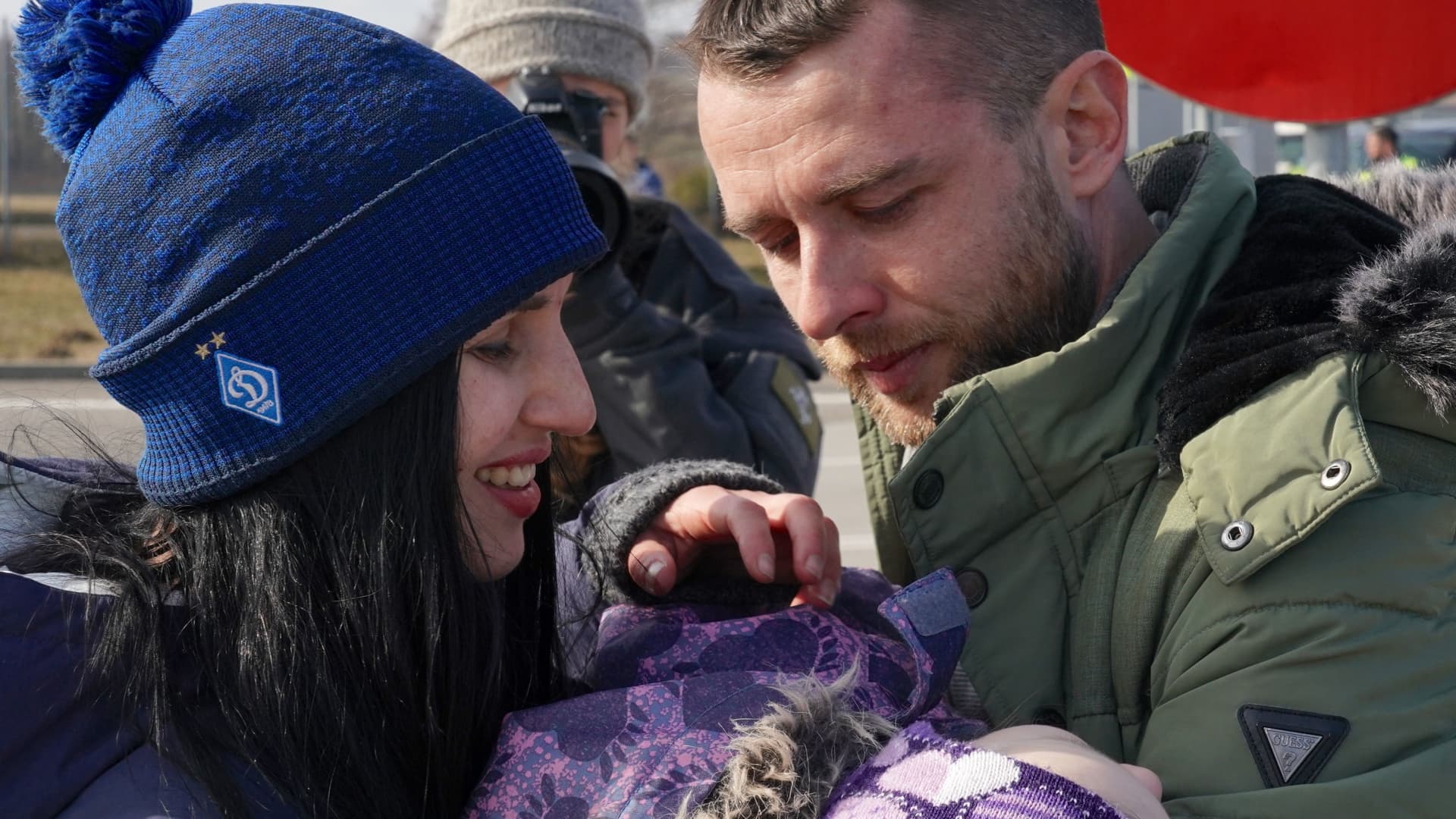 A Ukrainian man with a child welcomes his wife as Ukrainians cross the border from Ukraine to Poland at the Korczowa-Krakovets border crossing on February 26, 2022, following the Russian invasion of Ukraine.