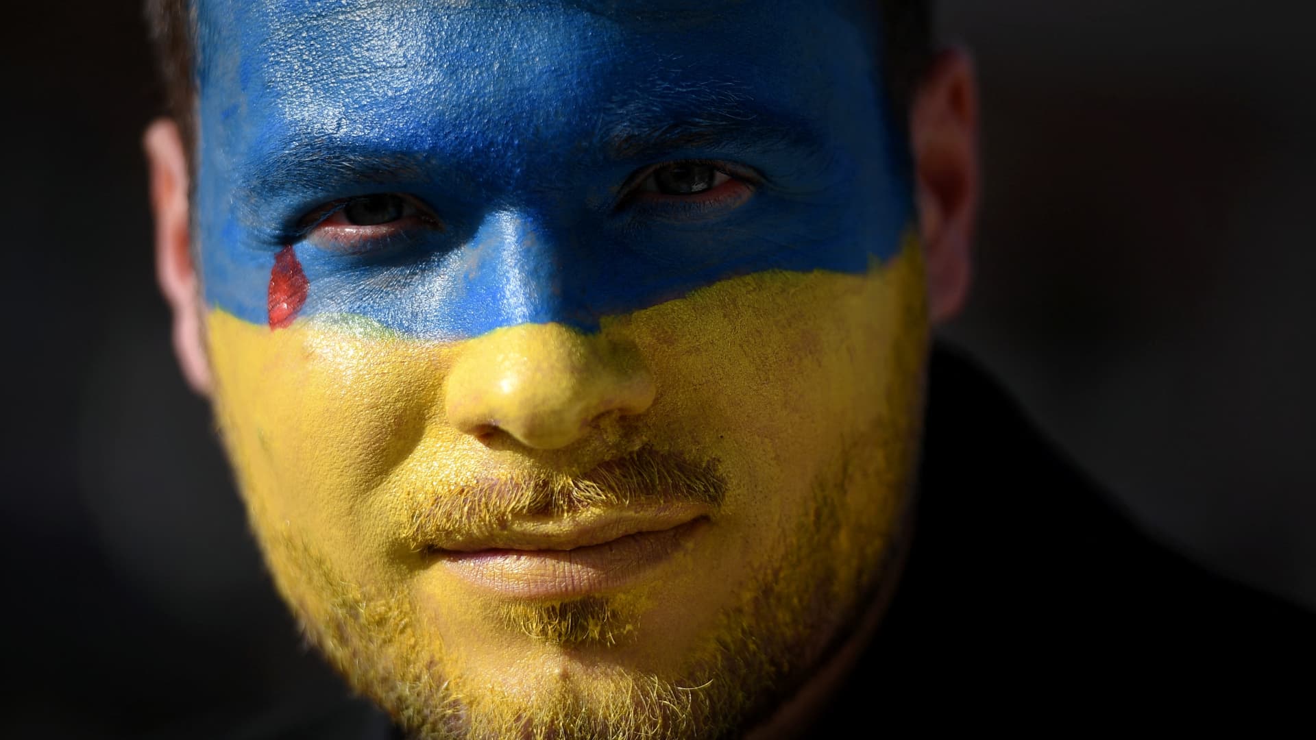A protester with blue and yellow make-up on his face, colours of the Ukrainian flag, attends a demonstration at the Place du Capitole, in Toulouse, southern France, on February 27, 2022, against the Russian invasion in Ukraine.