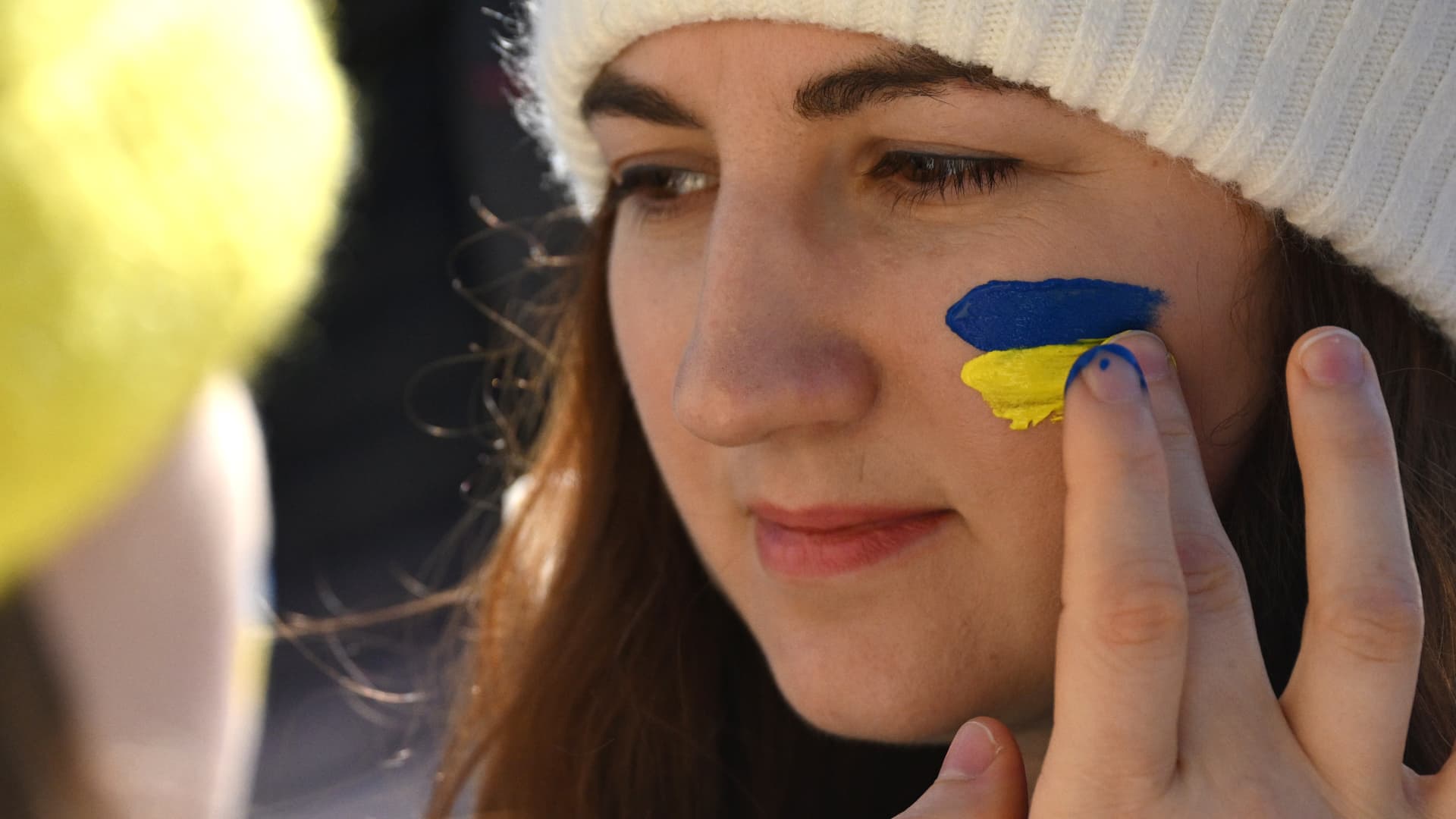 A protester finger paints a Ukrainian flag on another protester's face during a demonstration in support of Ukraine in Trafalgar Square on February 27, 2022 in London, England.