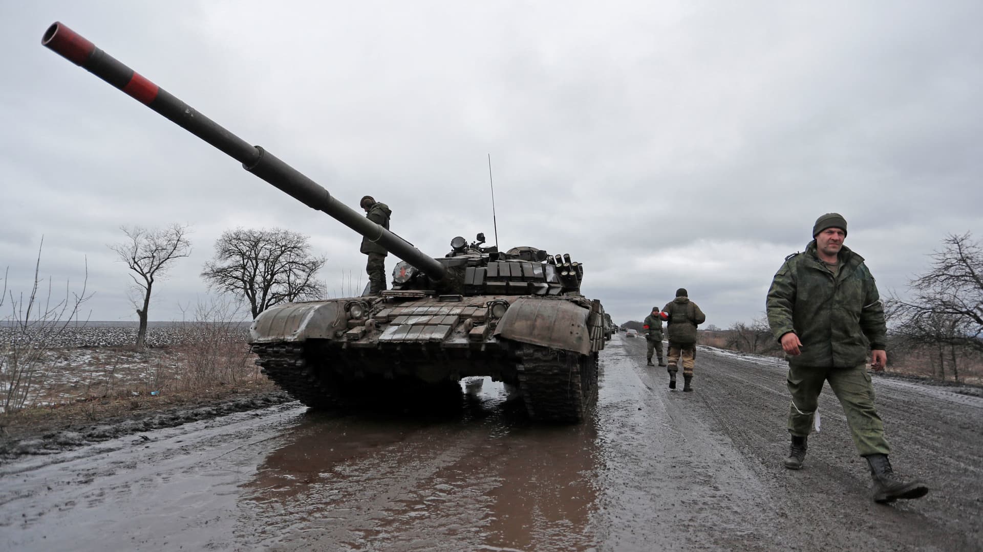 Servicemen of pro-Russian militia walk next to a military convoy of armed forces of the separatist self-proclaimed Luhansk People's Republic (LNR) on a road in the Luhansk region, Ukraine February 27, 2022.