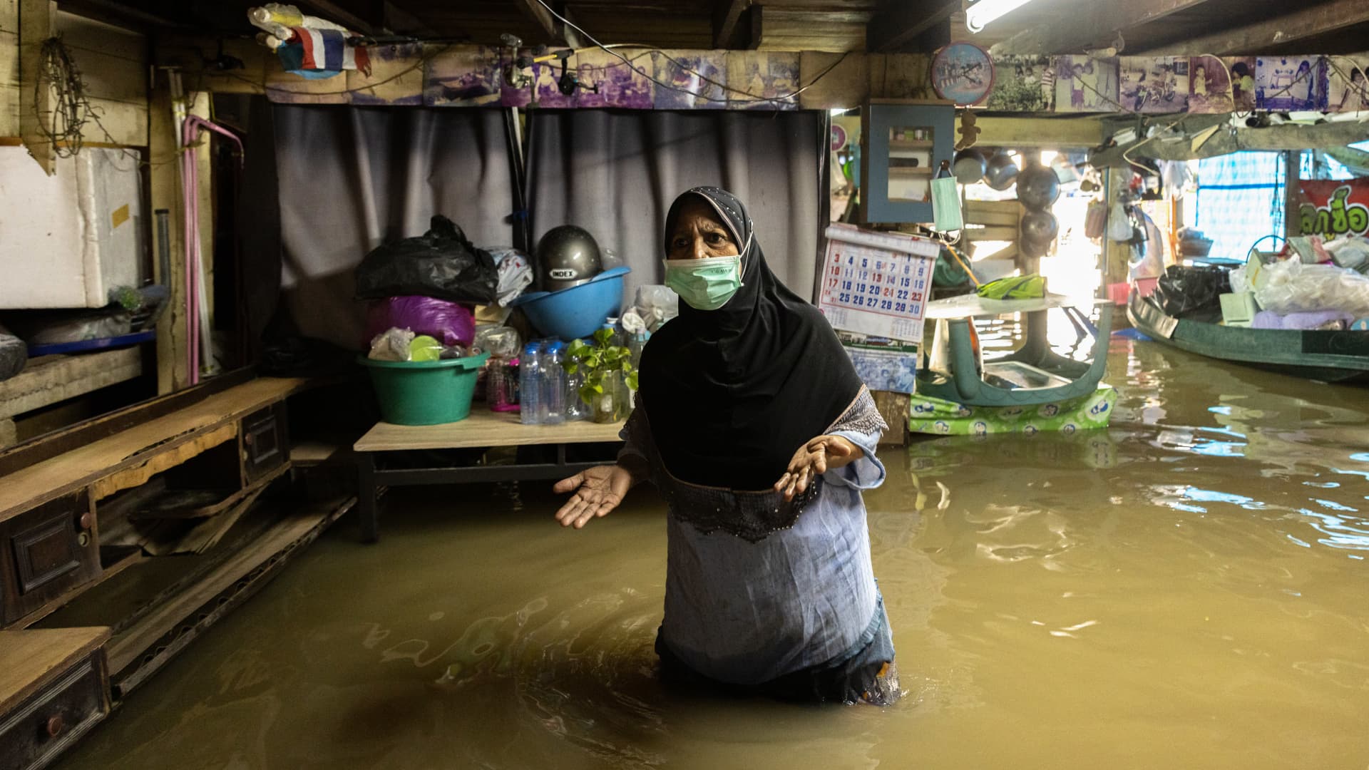 A woman is seen standing in her submerged house in October, 2021. Thailand has faced flash floods due to the heavy rainfall, tidal bore, and water drainage from Chao Phraya Dam after Dianmu Storm hit the country.