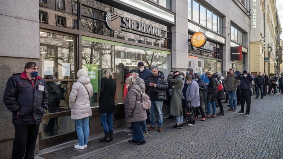 People queue outside a branch of Russian state-owned bank Sberbank to withdraw their savings and close their accounts in Prague on February 25, 2022, before Sberbank will close all its branches in the Czech Republic later in the day.