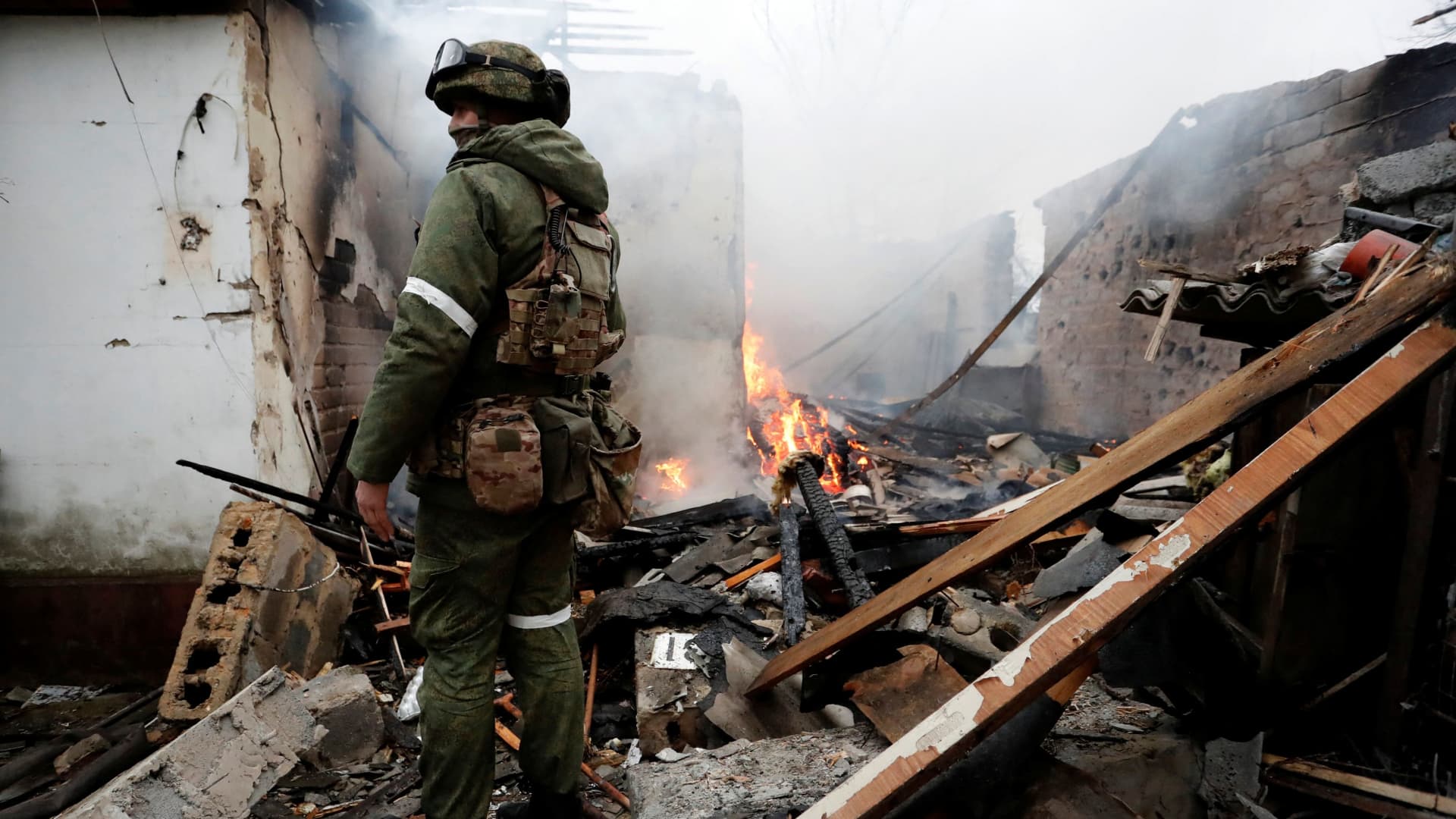 A serviceman of pro-Russian militia stands next to a house that caught fire after recent shelling, in the separatist-controlled city of Donetsk, Ukraine February 28, 2022.