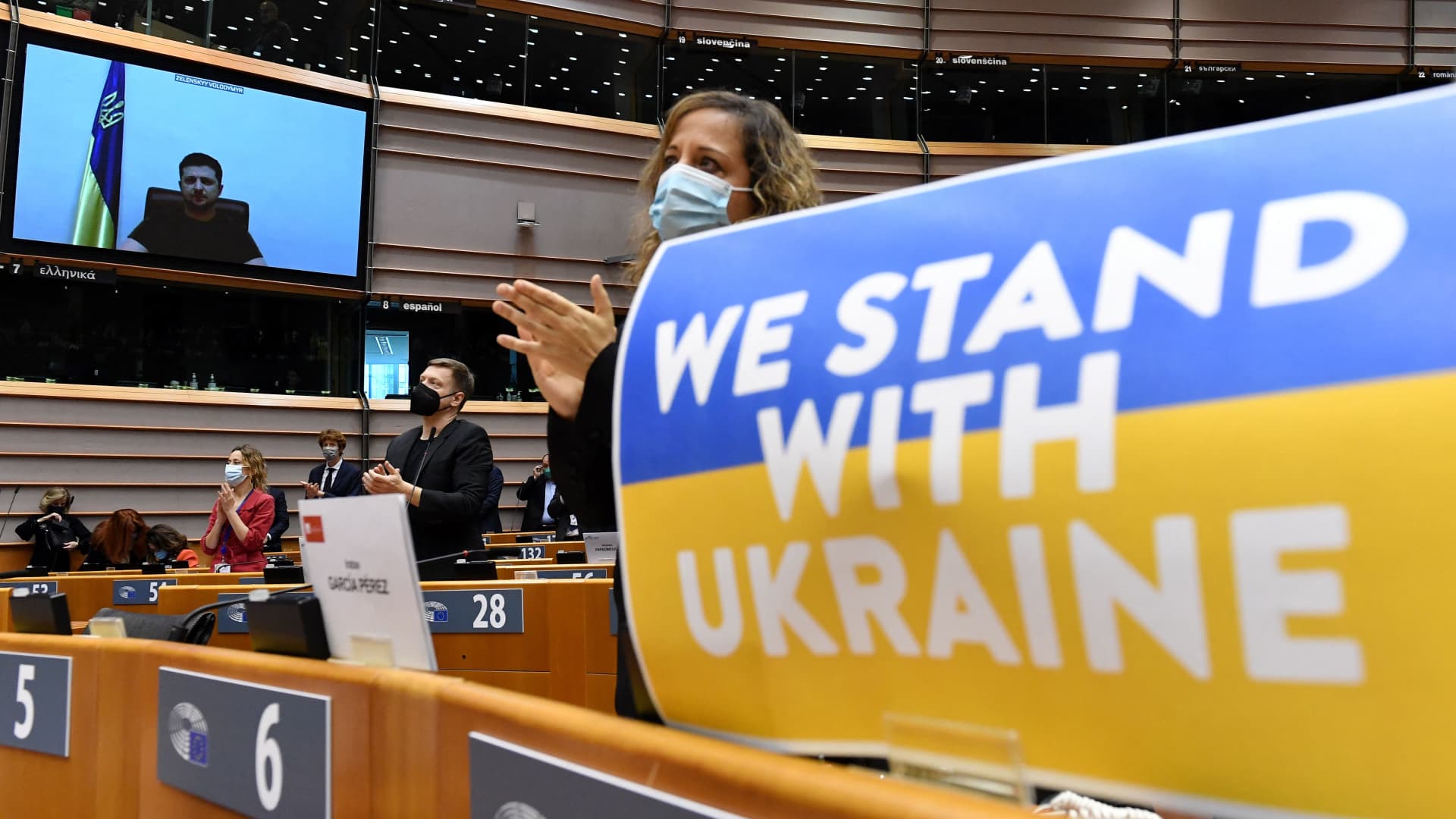 Members of the European Parliament applaud Ukrainian President Volodymyr Zelenskyy who appears on a screen as he speaks in a video conference during a special plenary session of the European Parliament focused on the Russian invasion of Ukraine at the EU headquarters in Brussels, on March 01, 2022.