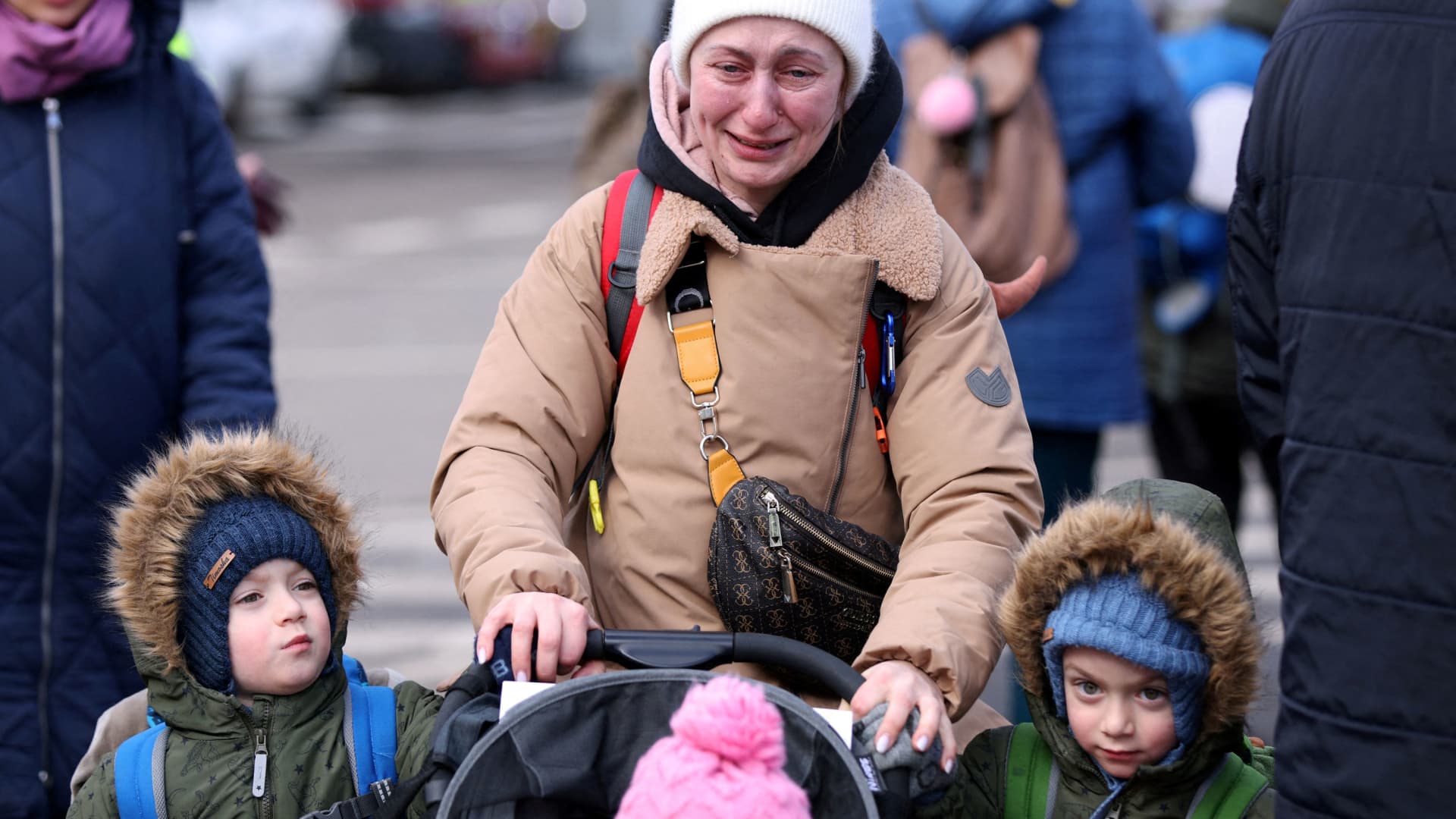 A woman cries next to her children after fleeing from Russia's invasion of Ukraine, at the border crossing in Siret, Romania, February 28, 2022.
