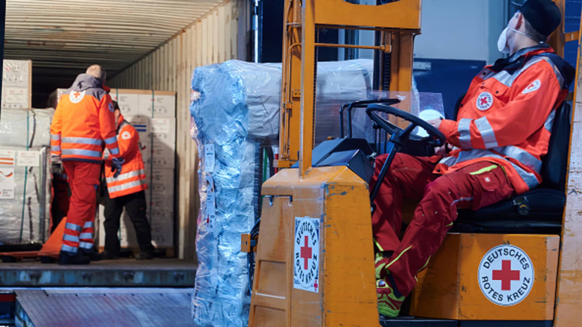 A truck is parked at the logistics center of the German Red Crossand is being loaded with relief supplies by employees.